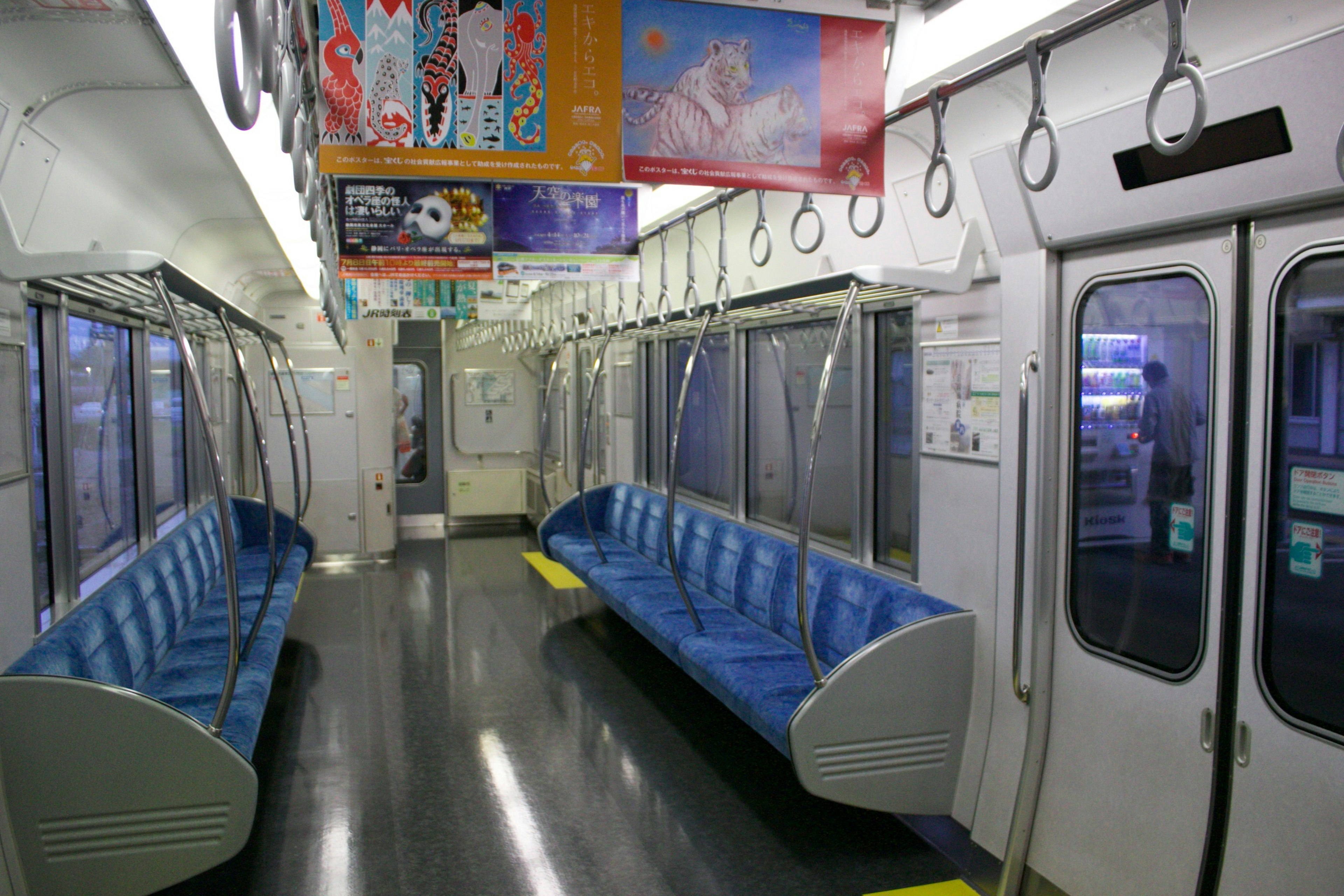 Interior of a subway train with blue seats and empty space