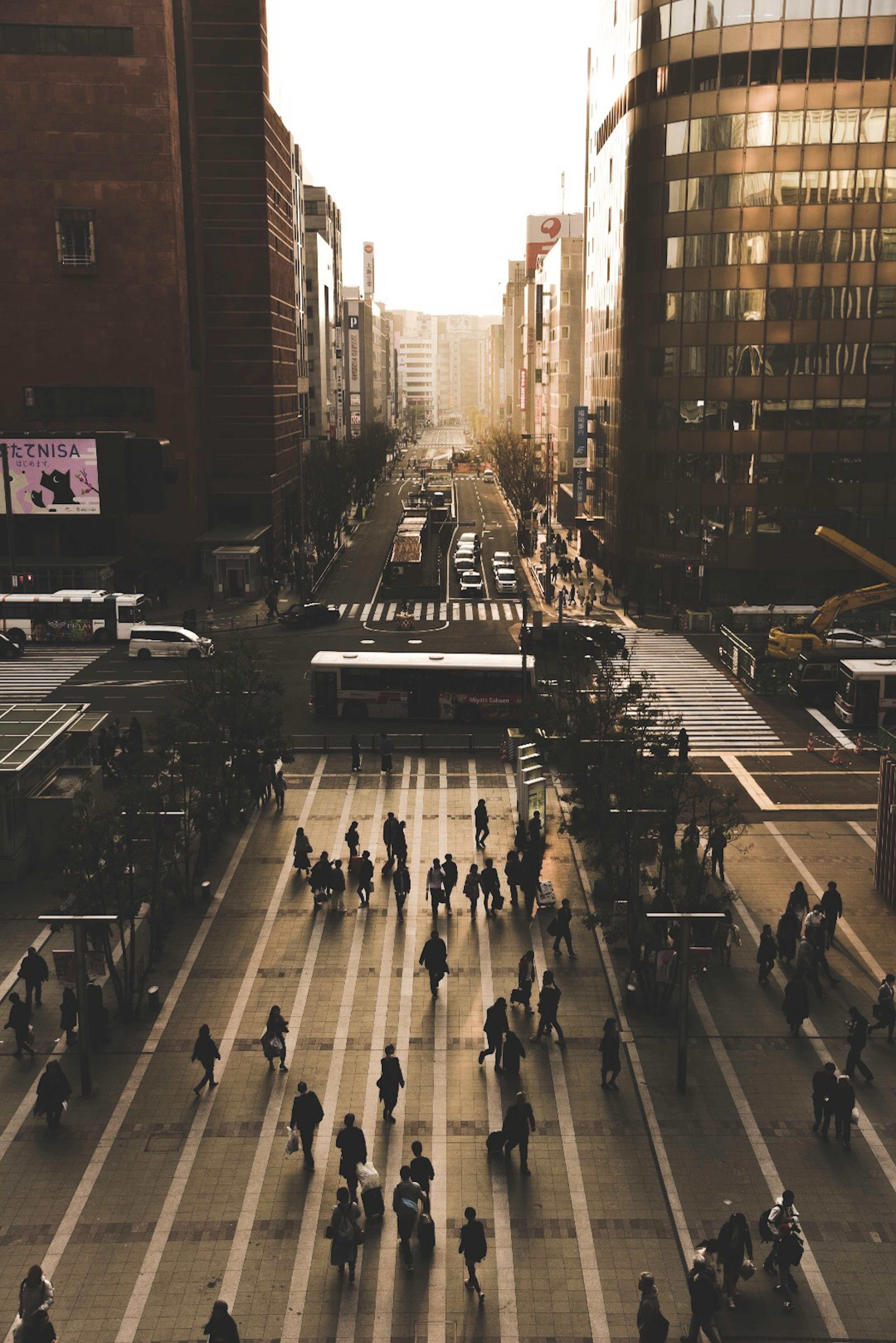 Urban landscape at dusk with people crossing an intersection among buildings