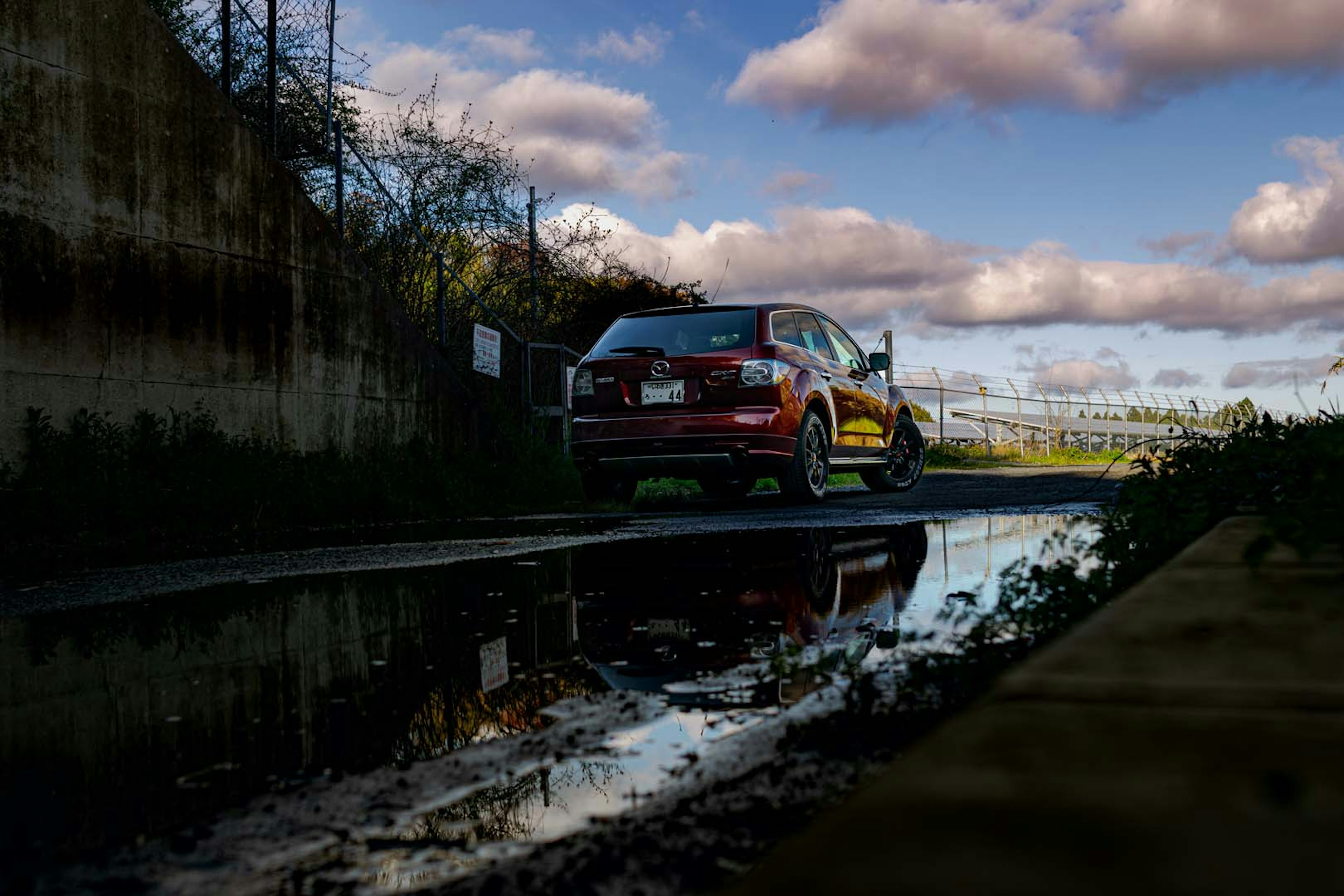 Car reflected in puddle with cloudy sky