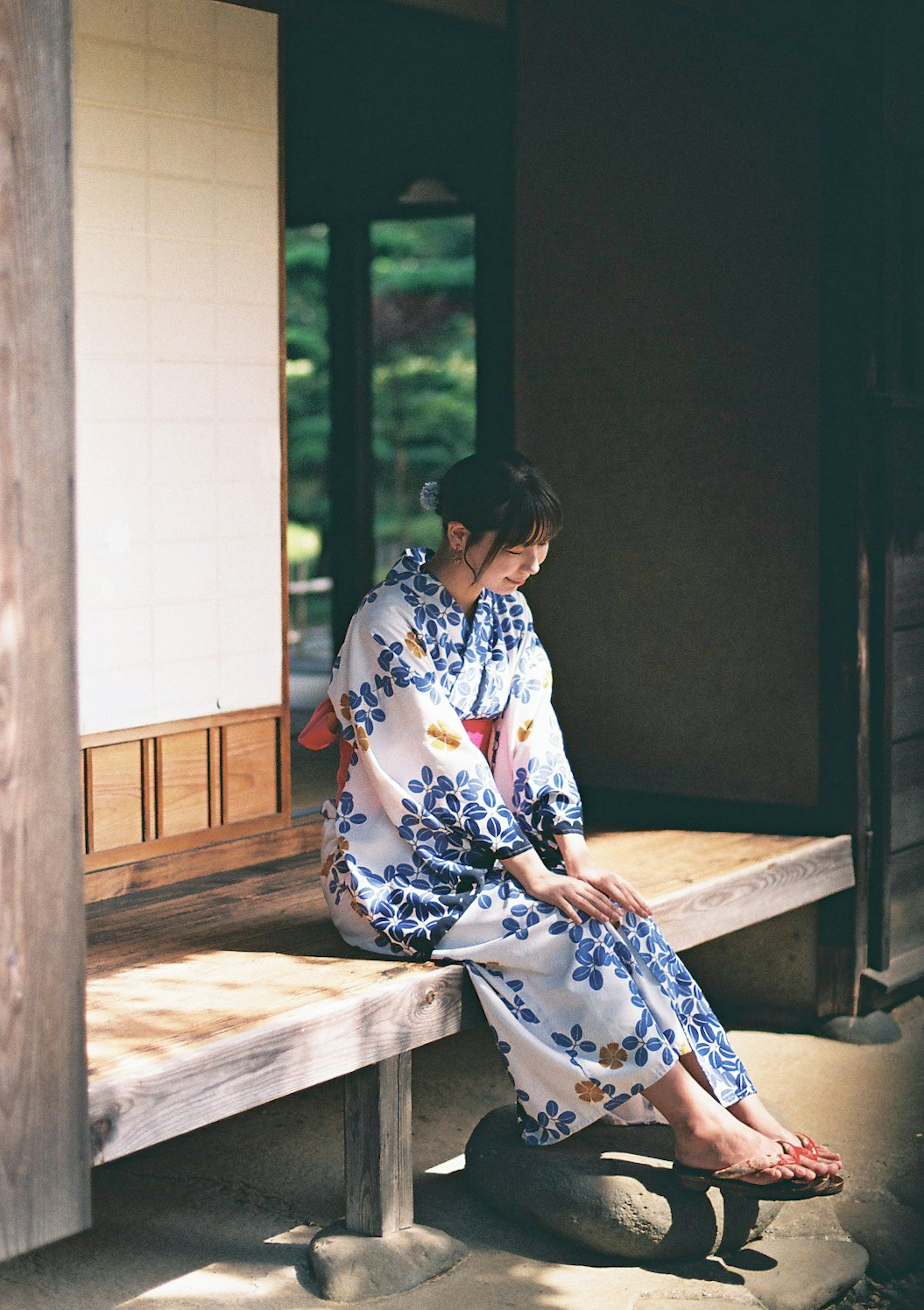 Seorang wanita dalam kimono duduk tenang di taman Jepang