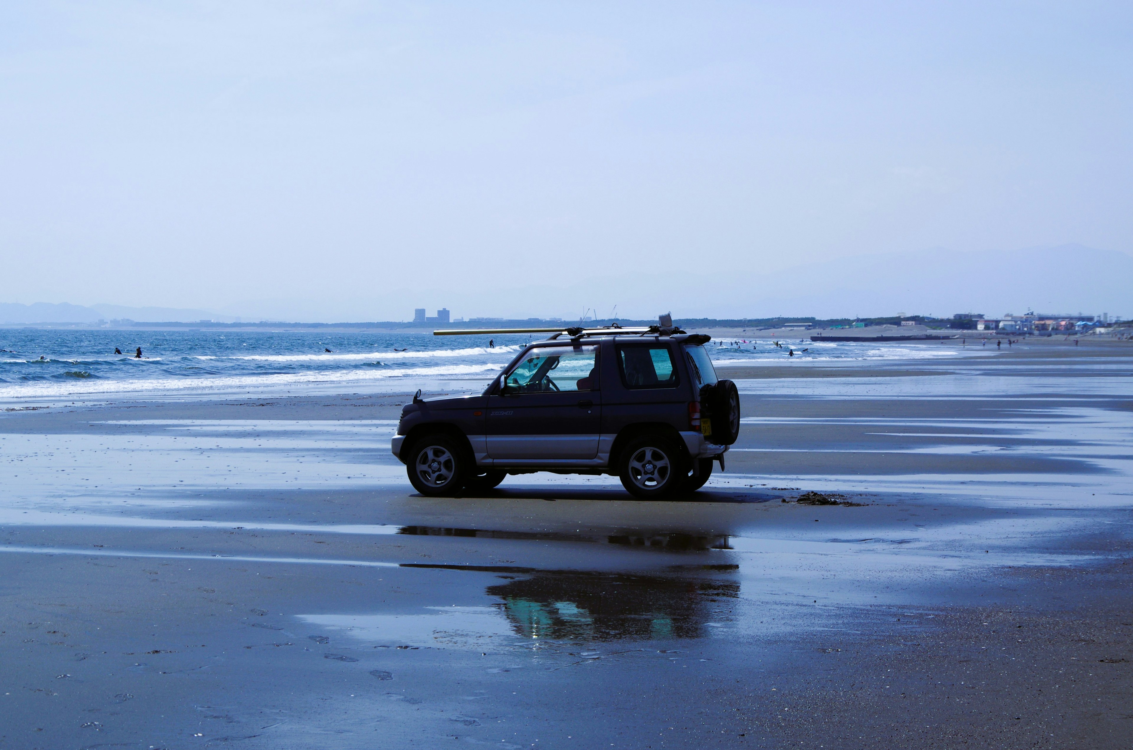 A black SUV parked on the beach shoreline