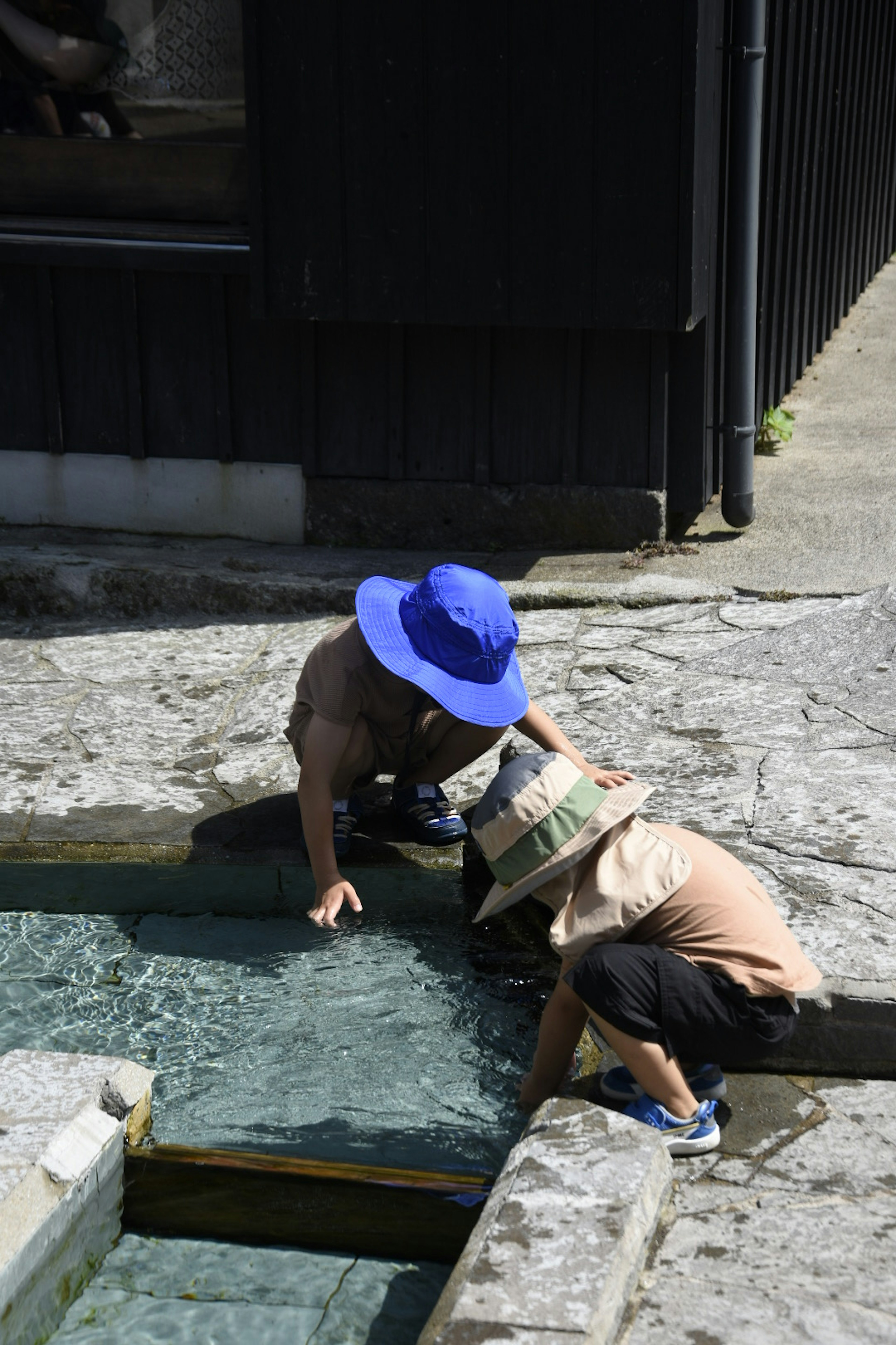 Children wearing blue and straw hats interacting with water