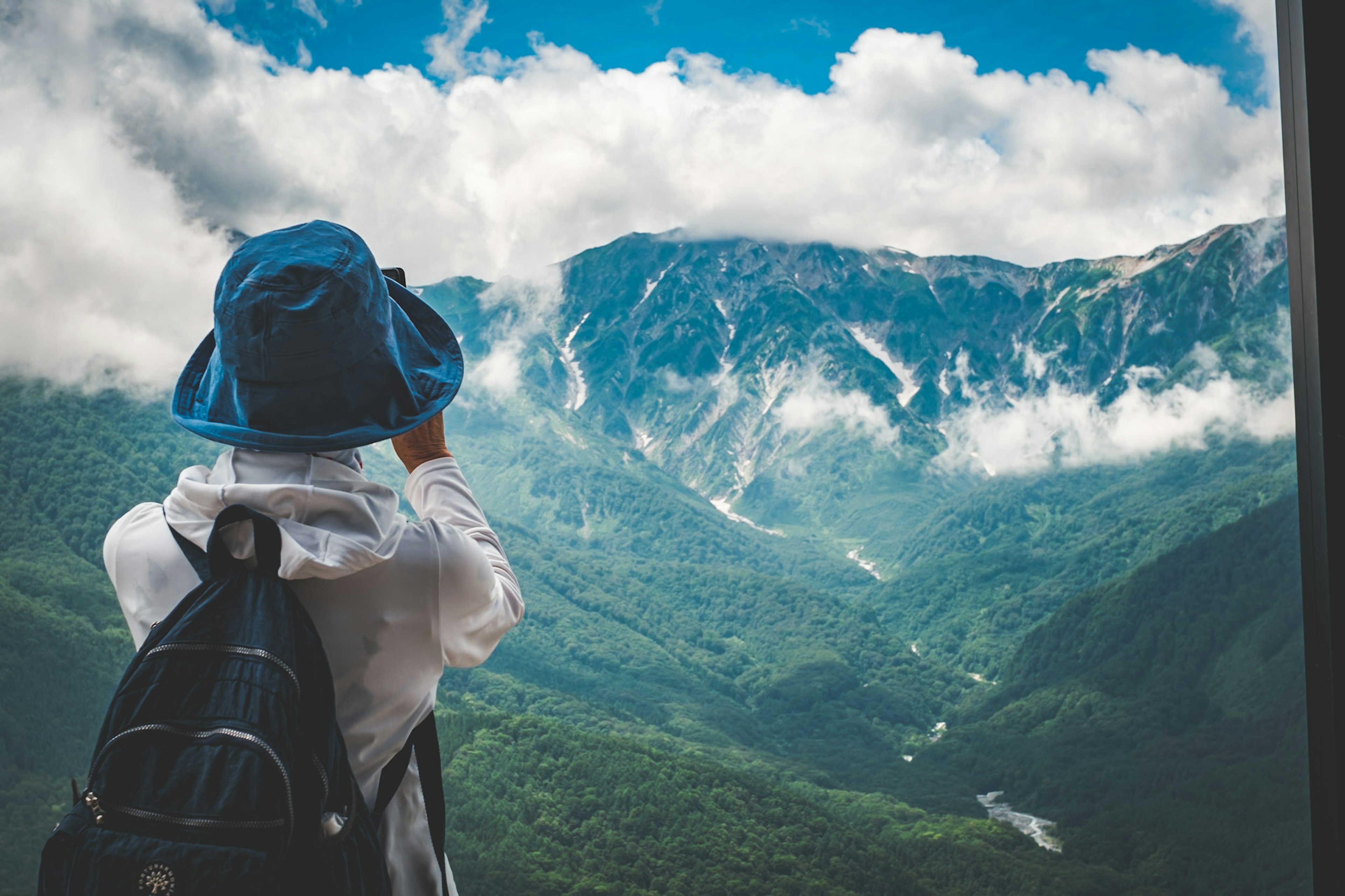 Personne portant un chapeau bleu regardant un paysage de montagne