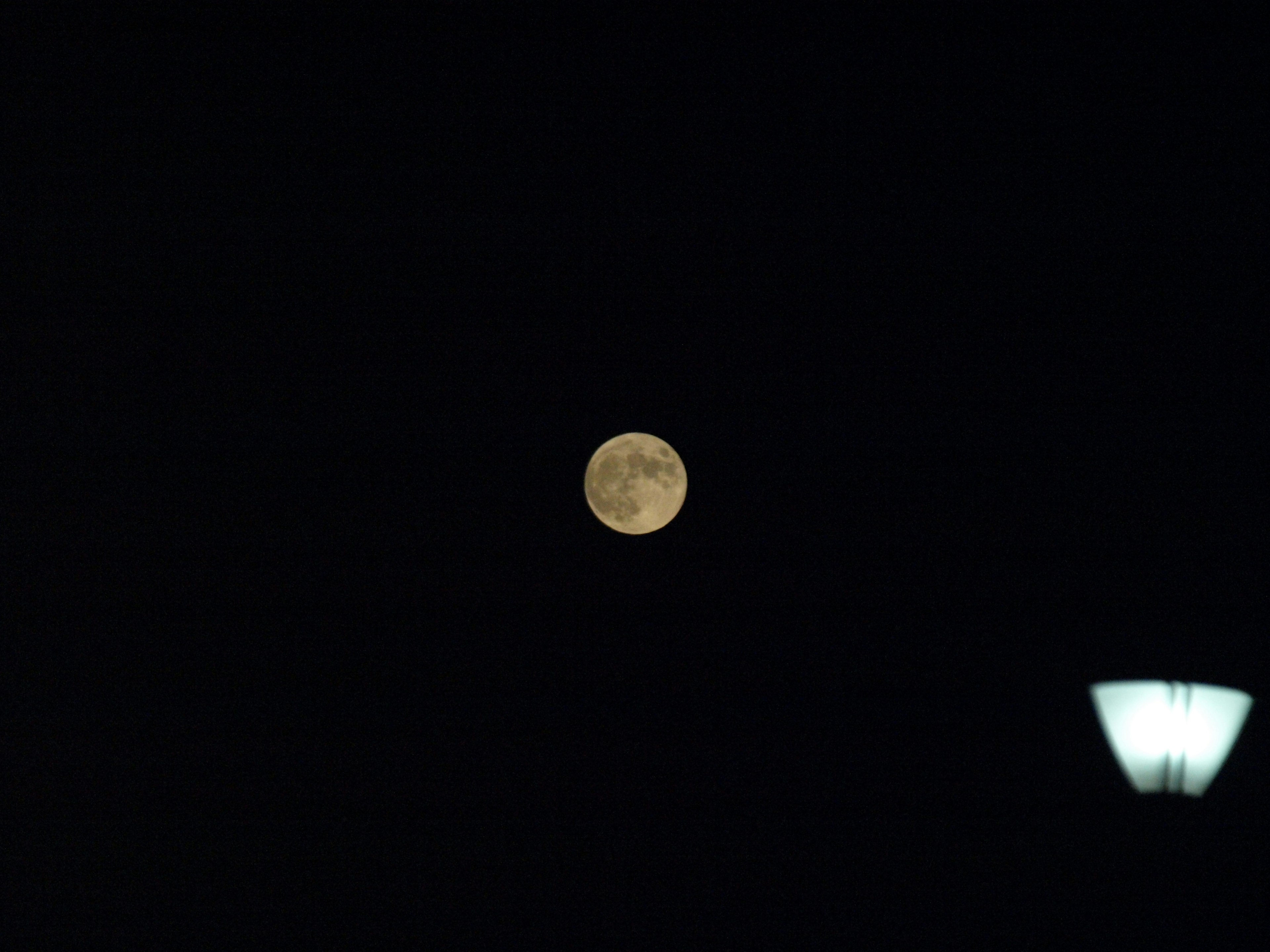 Bright moon in the night sky with a streetlamp