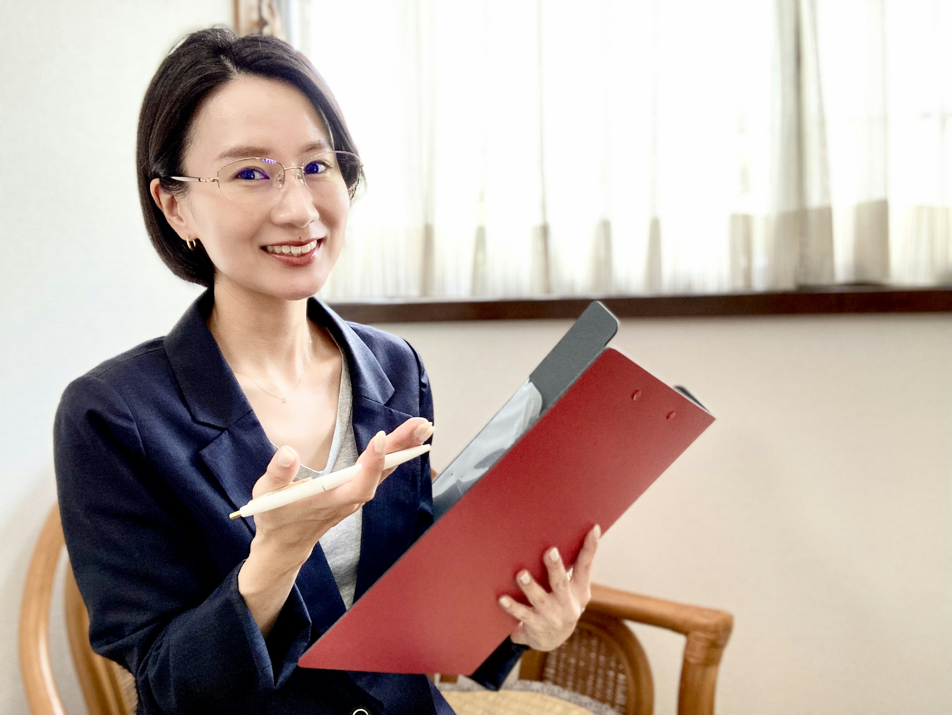 Femme jeune souriante tenant un dossier rouge