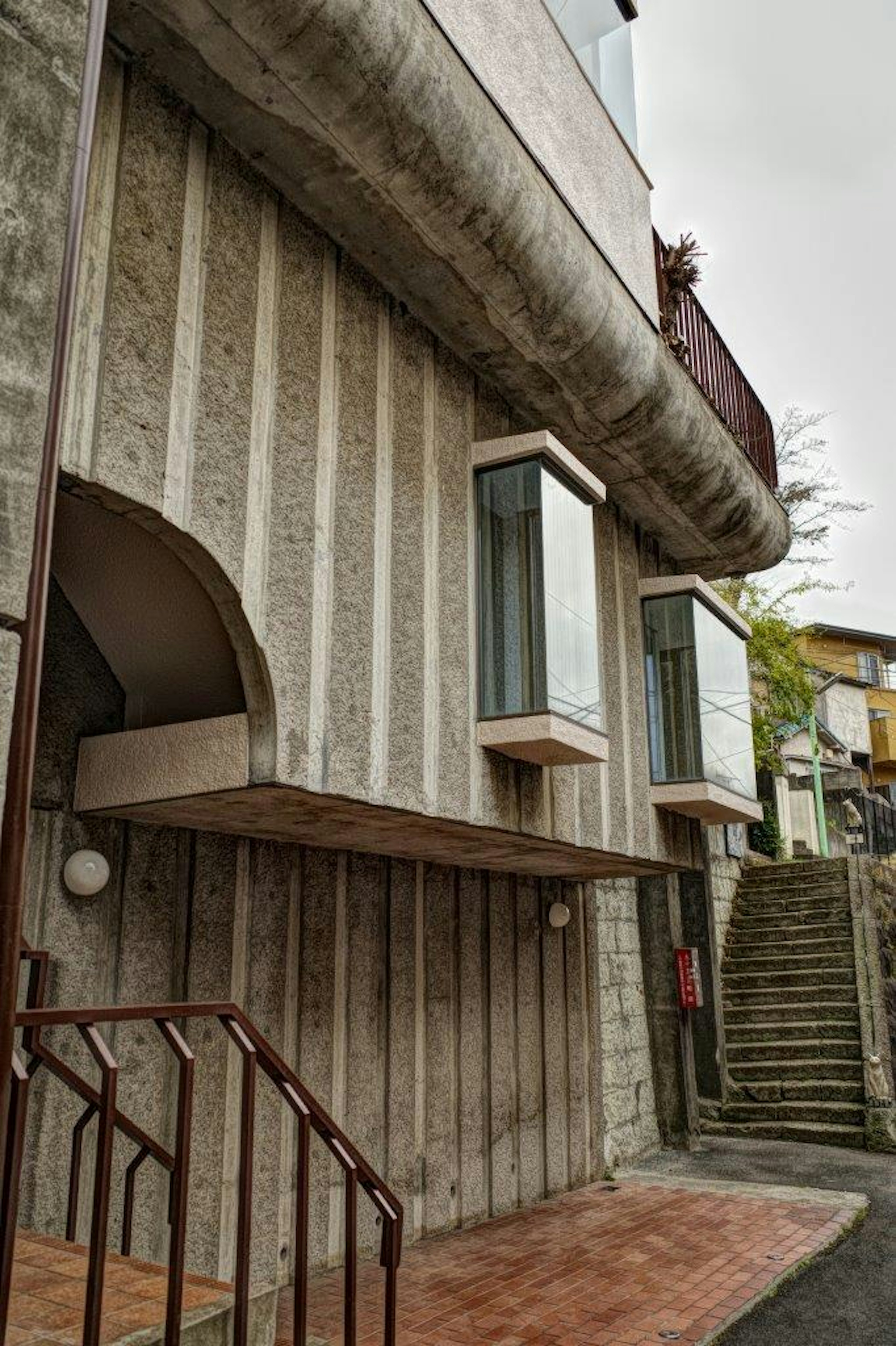 Vue extérieure d'un bâtiment en béton unique avec des fenêtres distinctives et des escaliers visibles