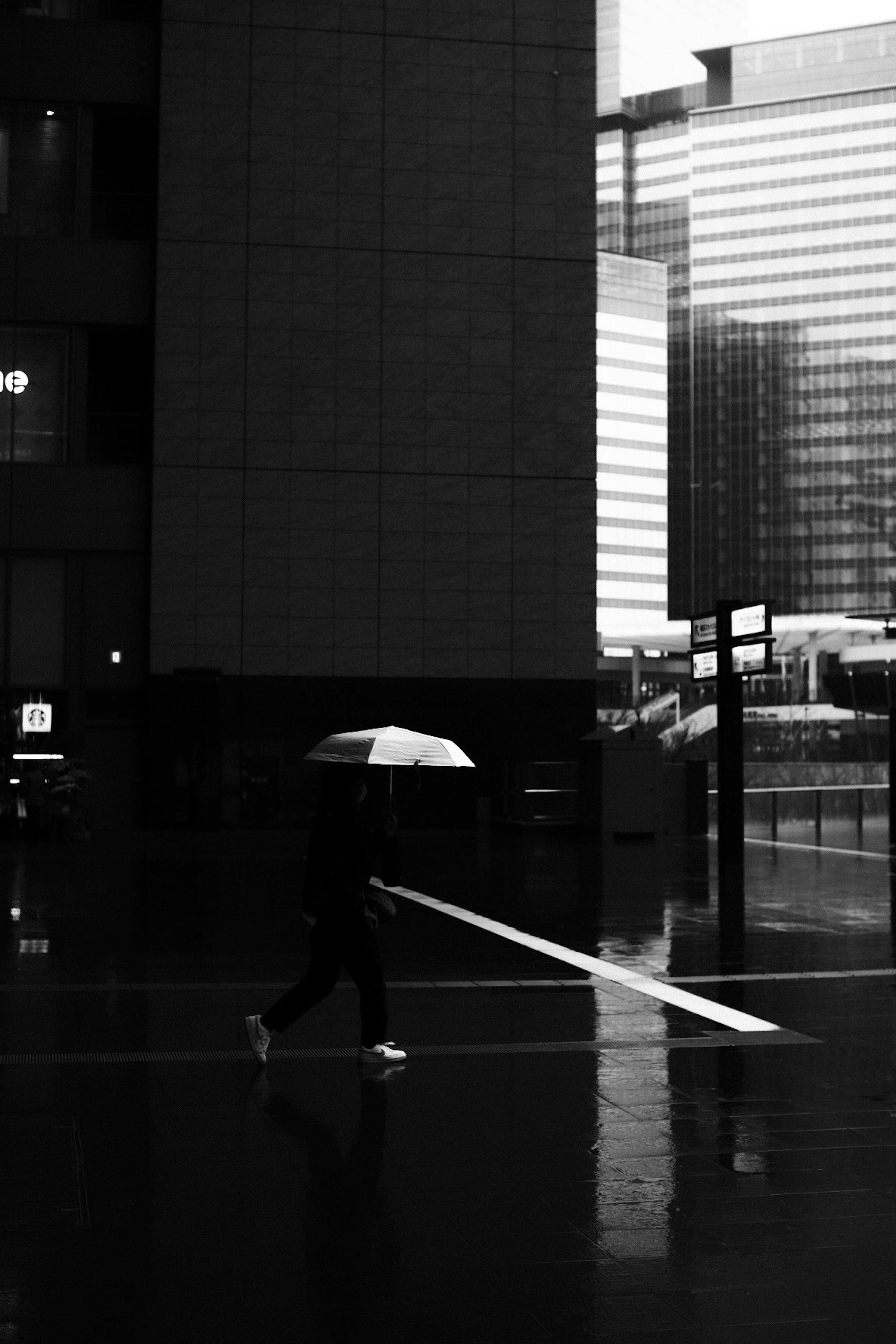 Silhouette di una persona che cammina con un ombrello sotto la pioggia