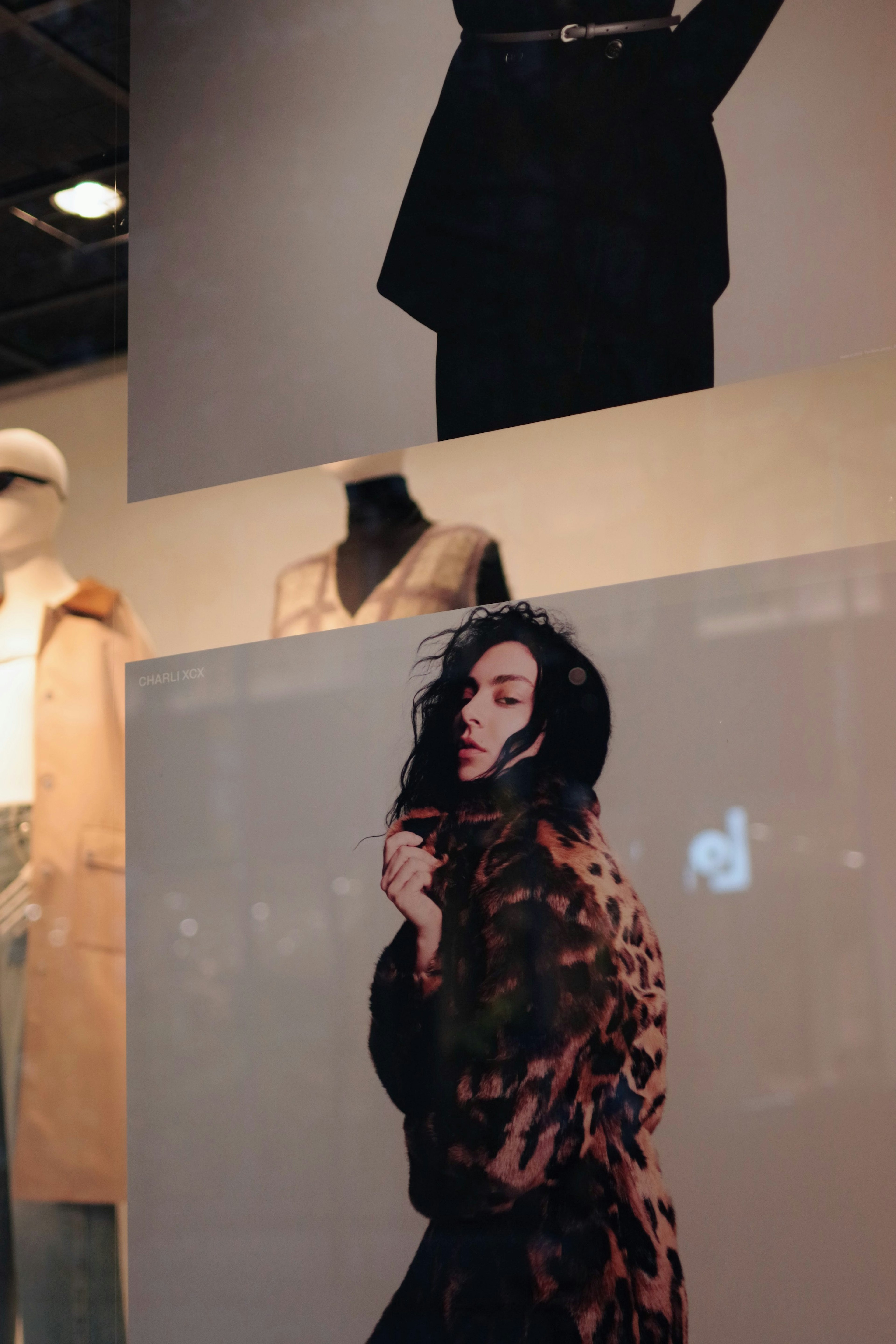 Fashion window display featuring garments and a model The model wears a leopard print coat