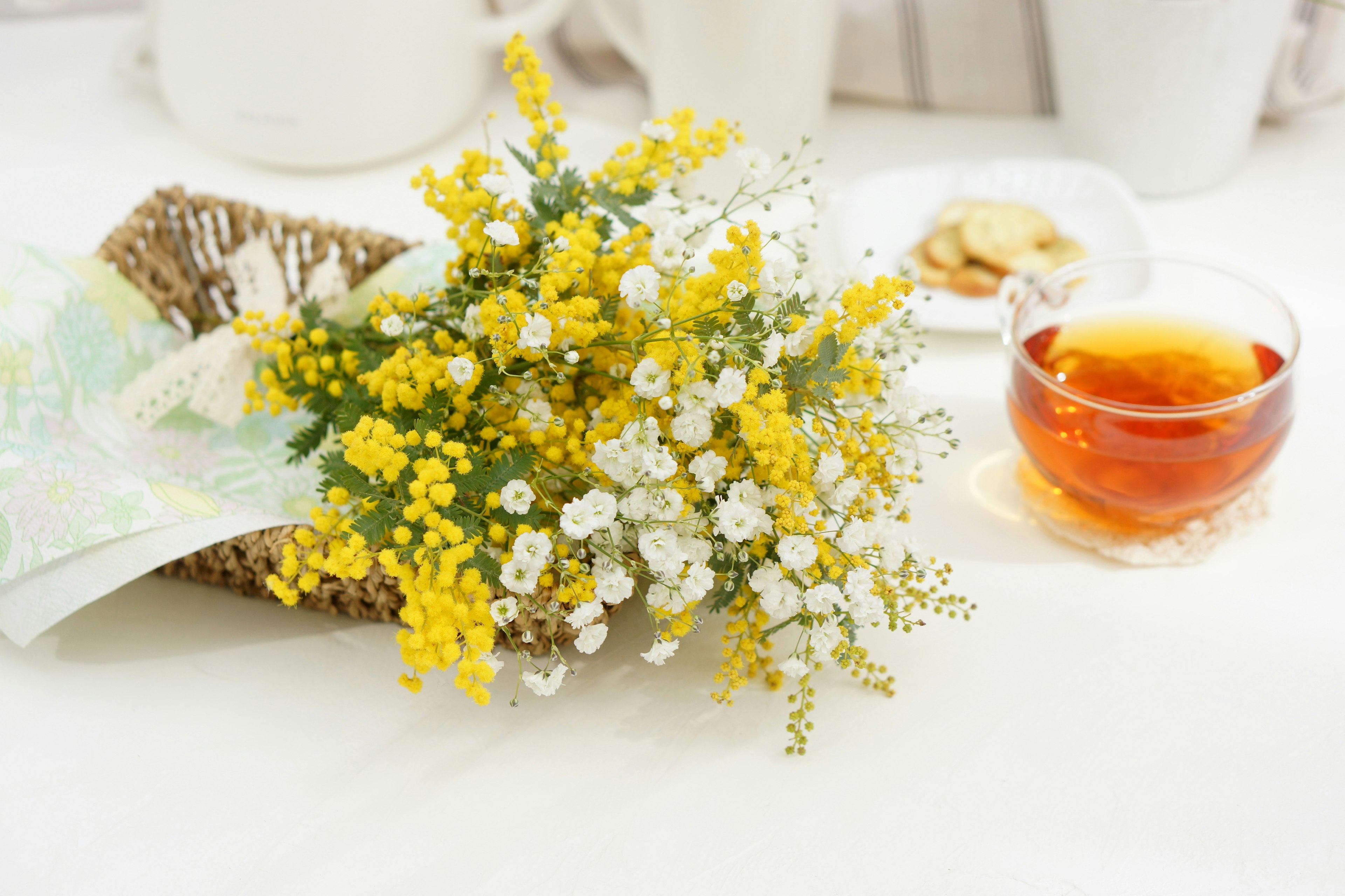 Un'impostazione semplice della tavola con un mazzo di fiori gialli e bianchi e una tazza di tè