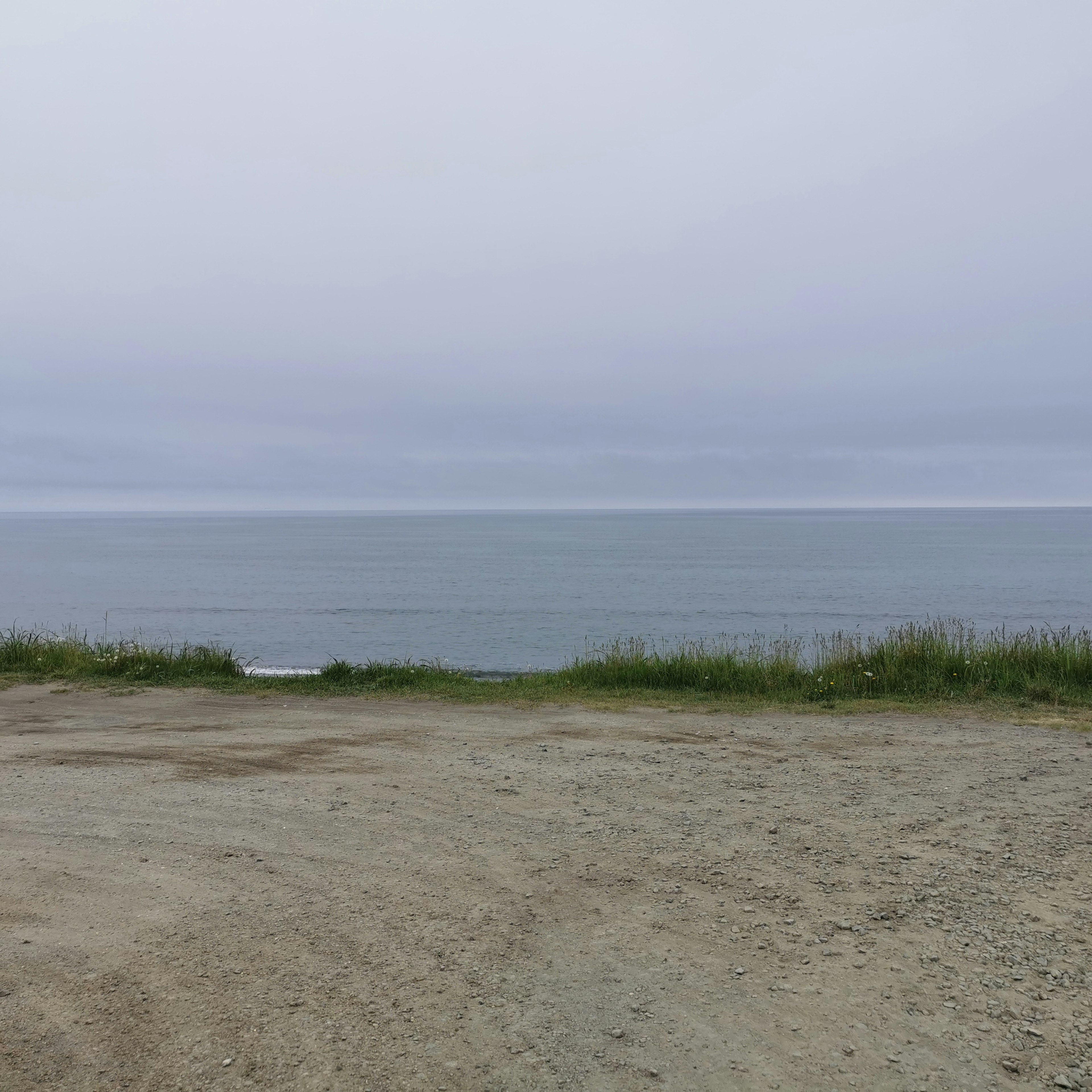 Pemandangan pantai dengan laut tenang di bawah langit mendung