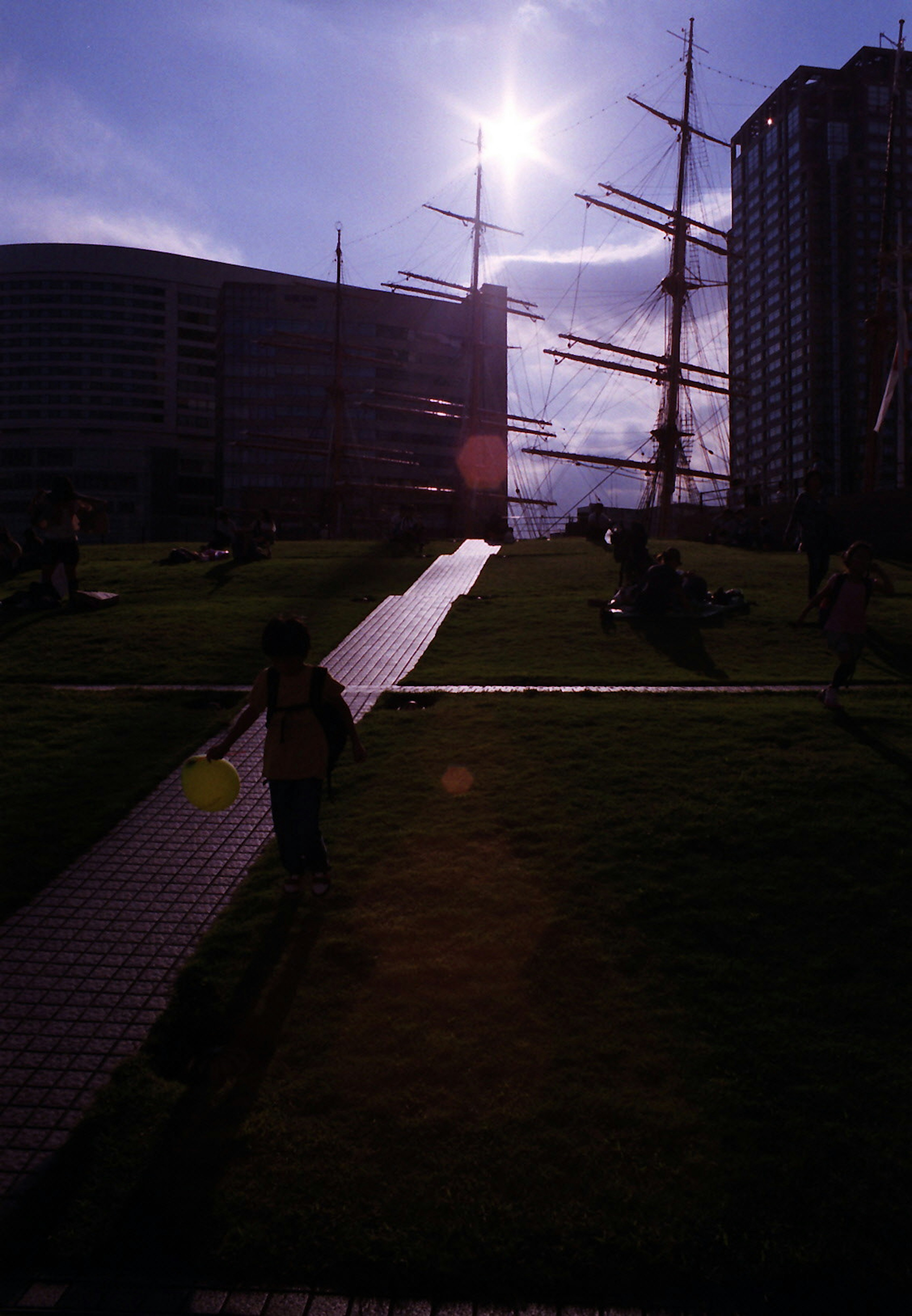 Silhouette von Kindern, die in einem Park mit einem Schiff und hellen Sonnenuntergang spielen