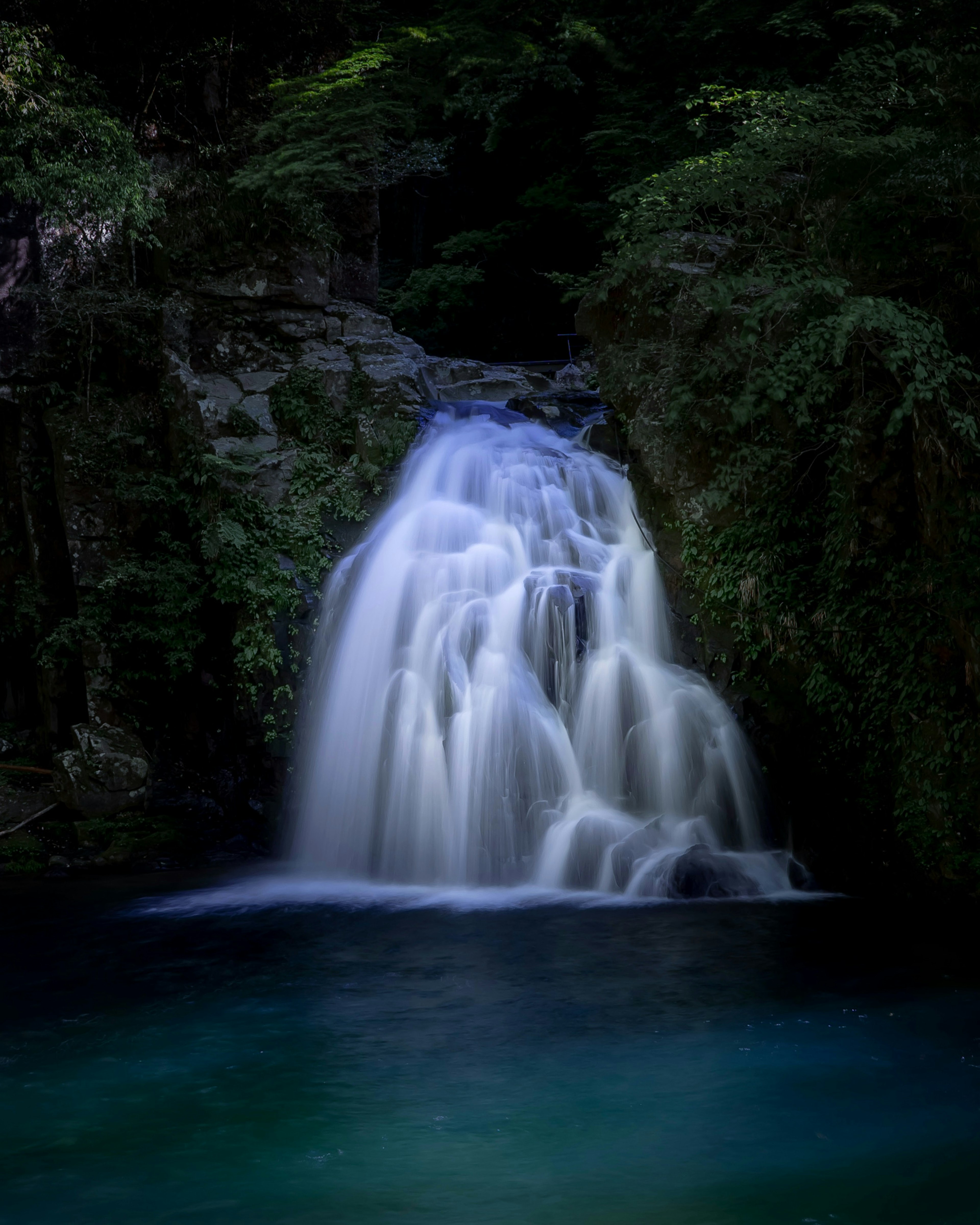 Ein ruhiger Wasserfall, der in einen friedlichen Pool fällt, umgeben von üppigem Grün