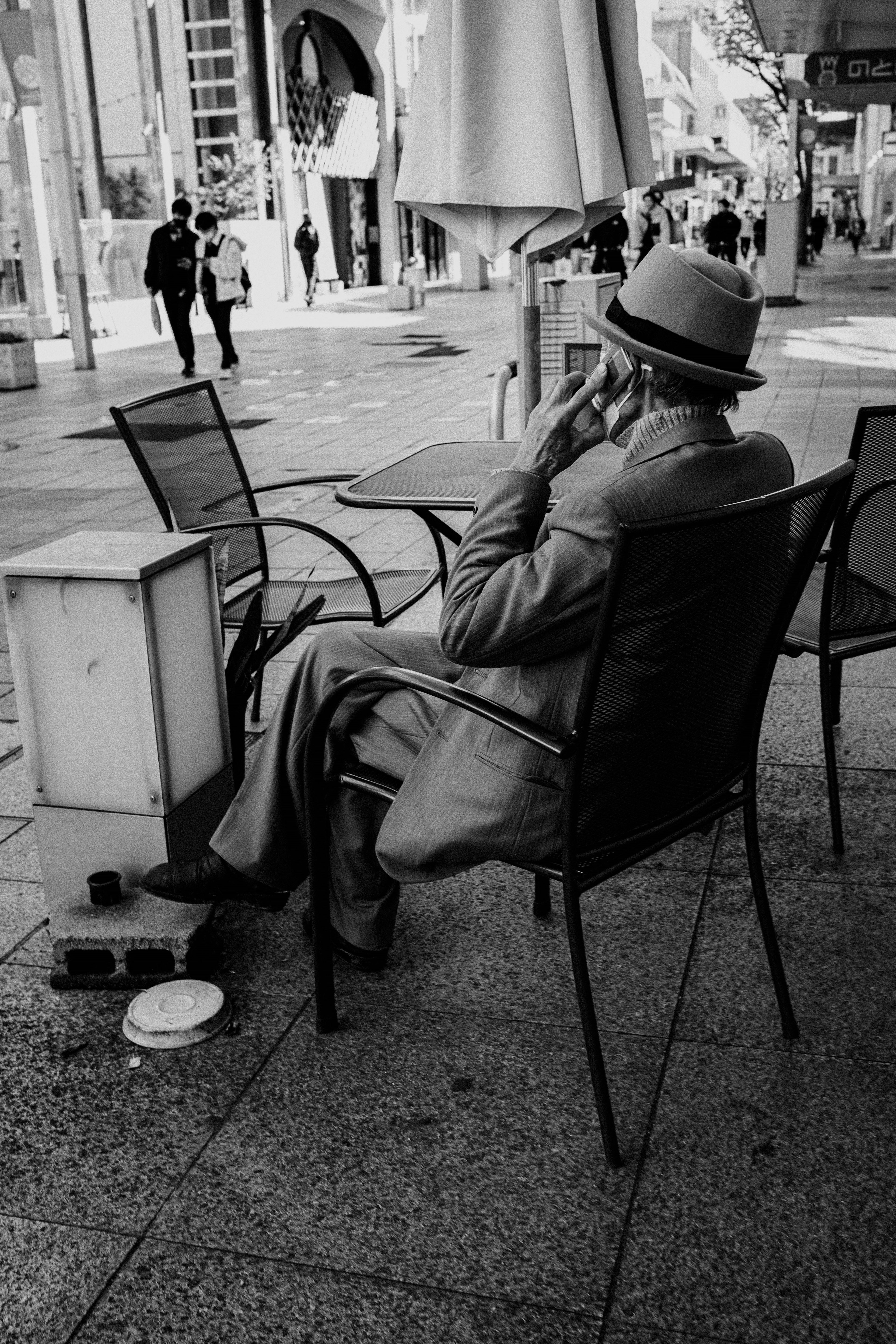 街のカフェで喫煙する男性の後ろ姿と周囲の風景