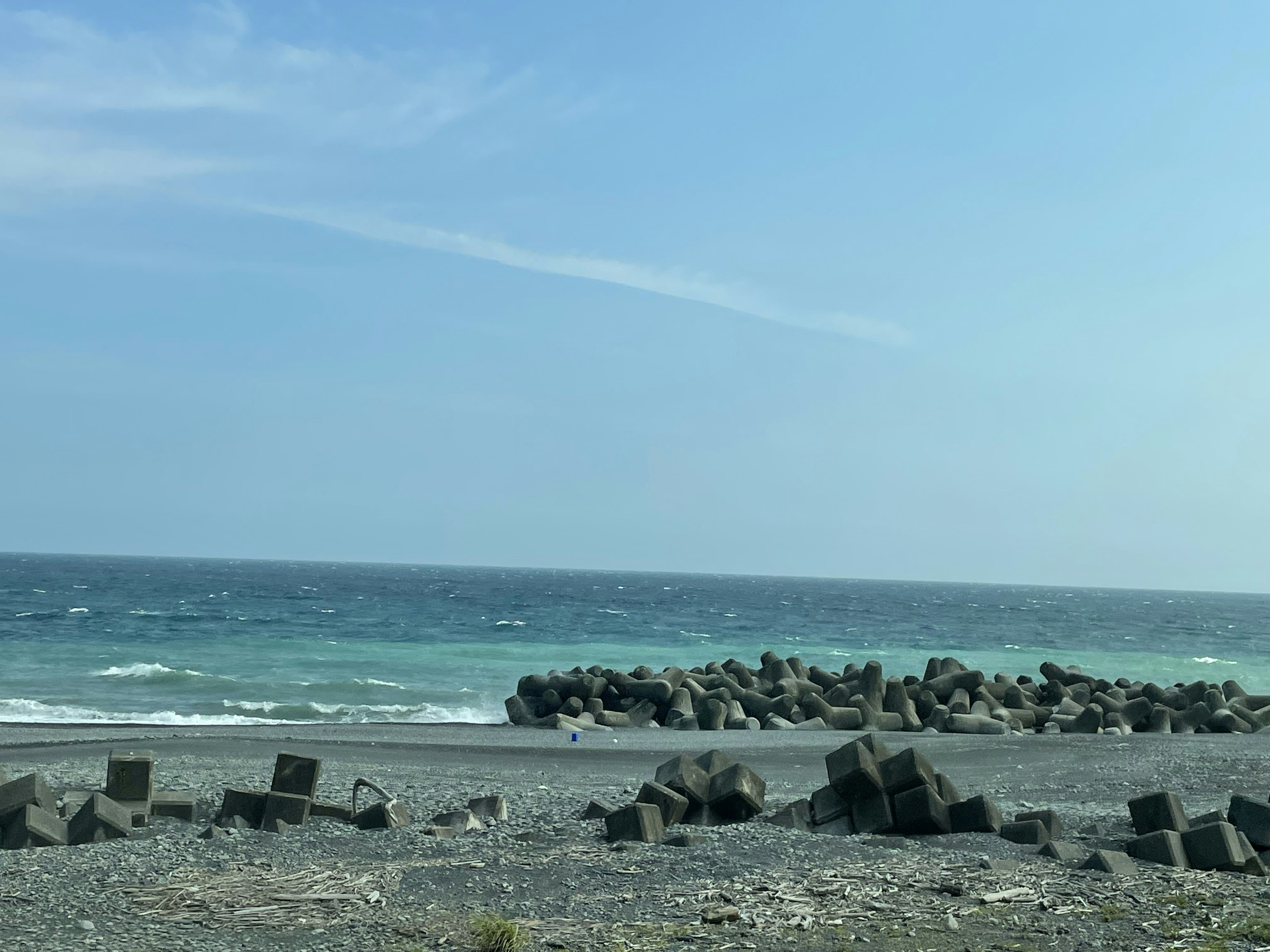 Strandszene mit blauen Wellen und Betonblöcken am Ufer