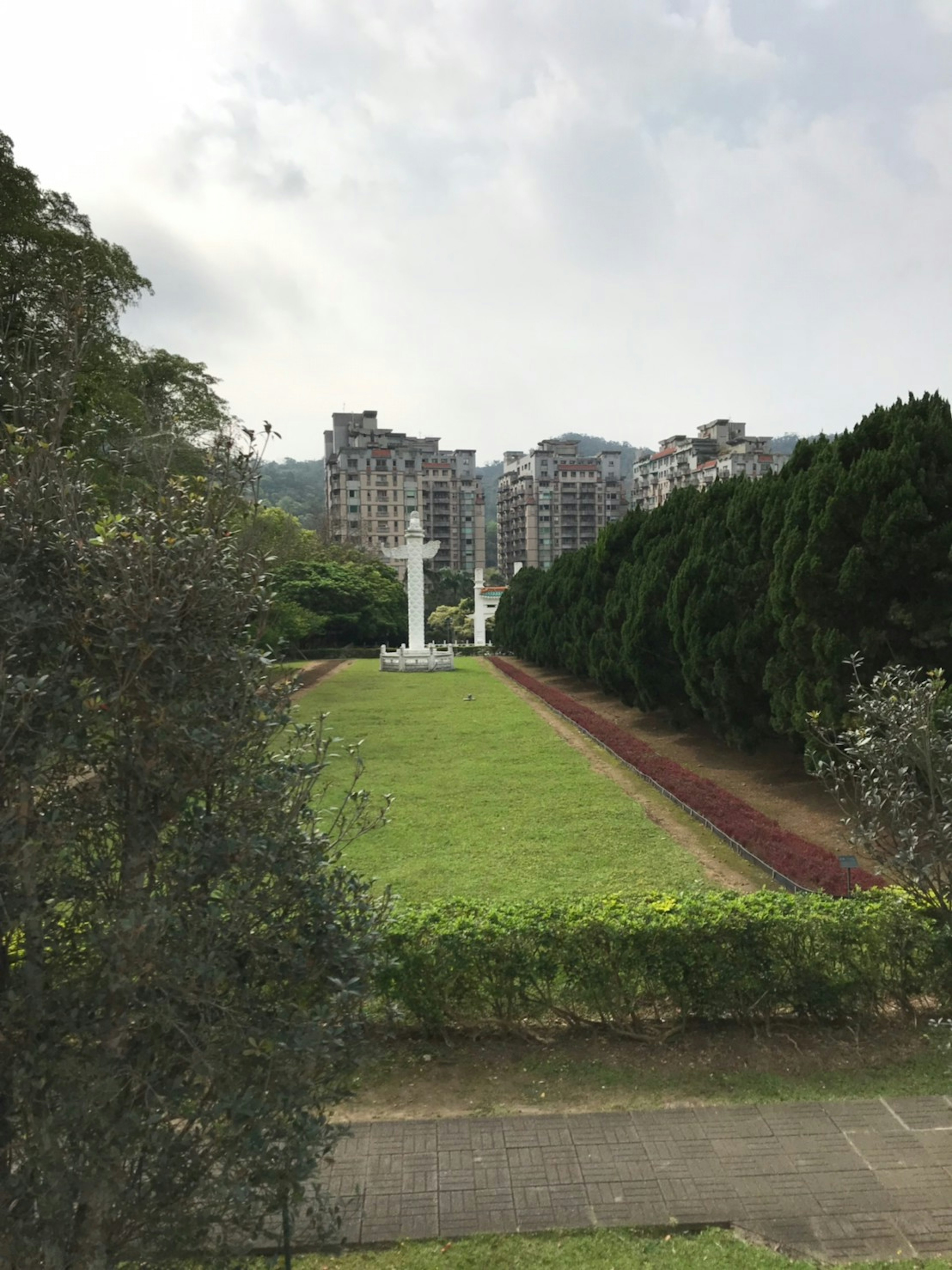 白い柱が立つ公園の景色 周囲には緑の木々と高層ビルが見える