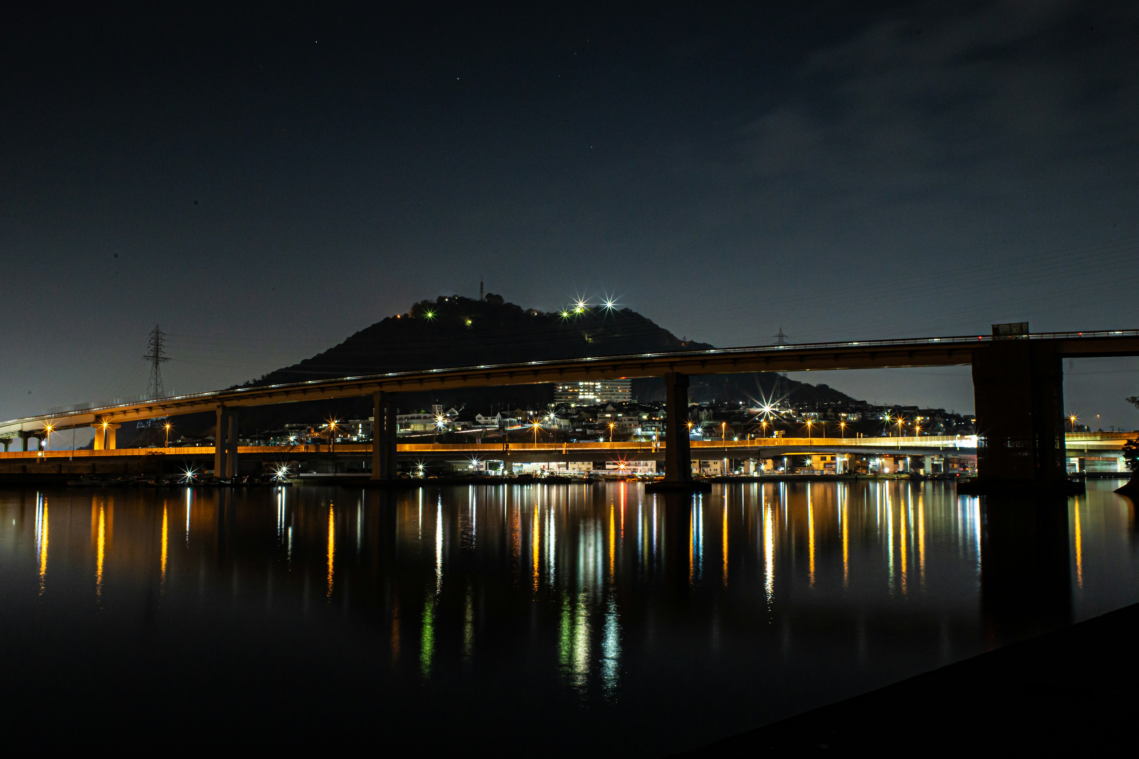 Vue nocturne d'un pont et d'une montagne se reflétant dans l'eau calme