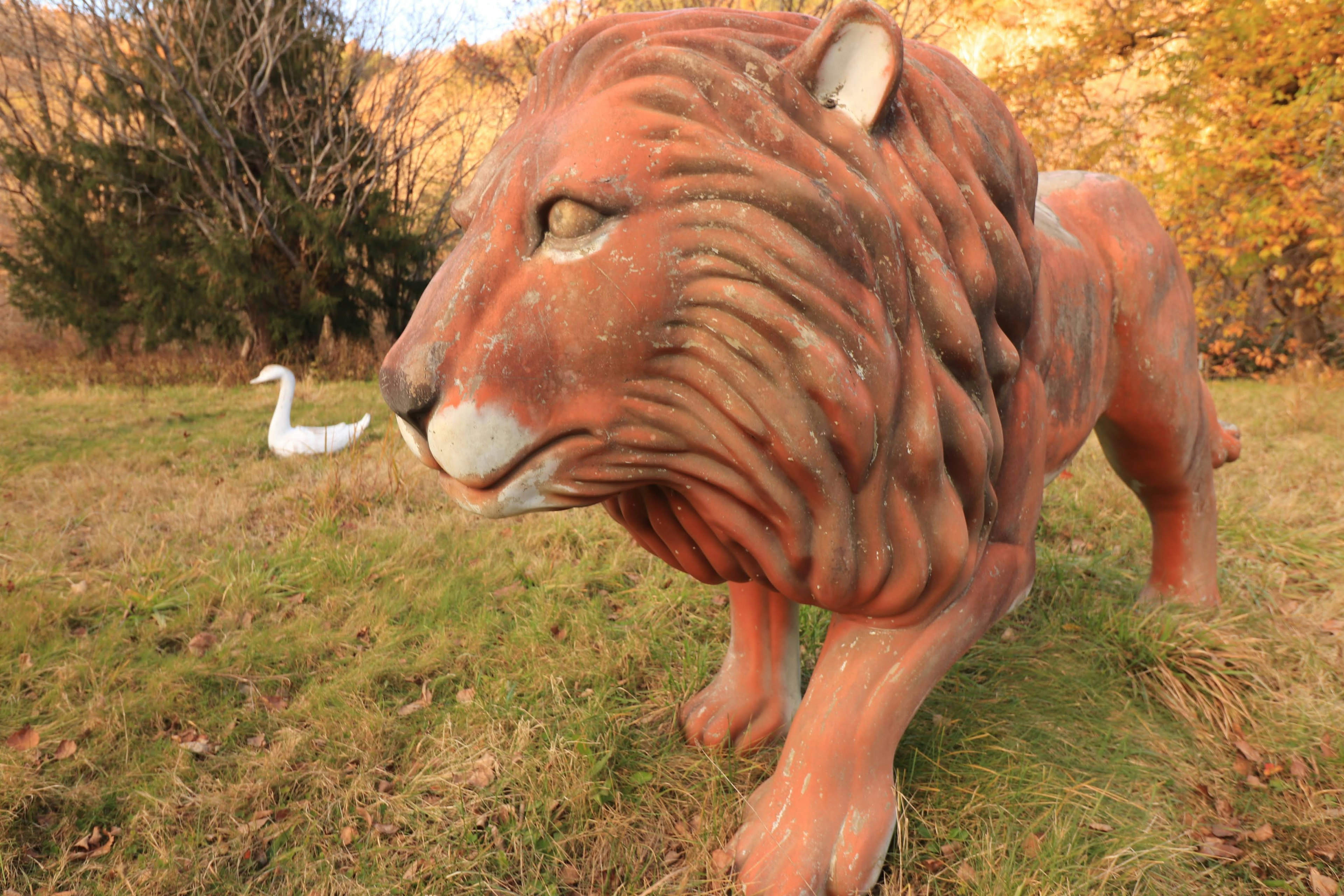 Gran escultura de león en un parque con un ave blanca al fondo