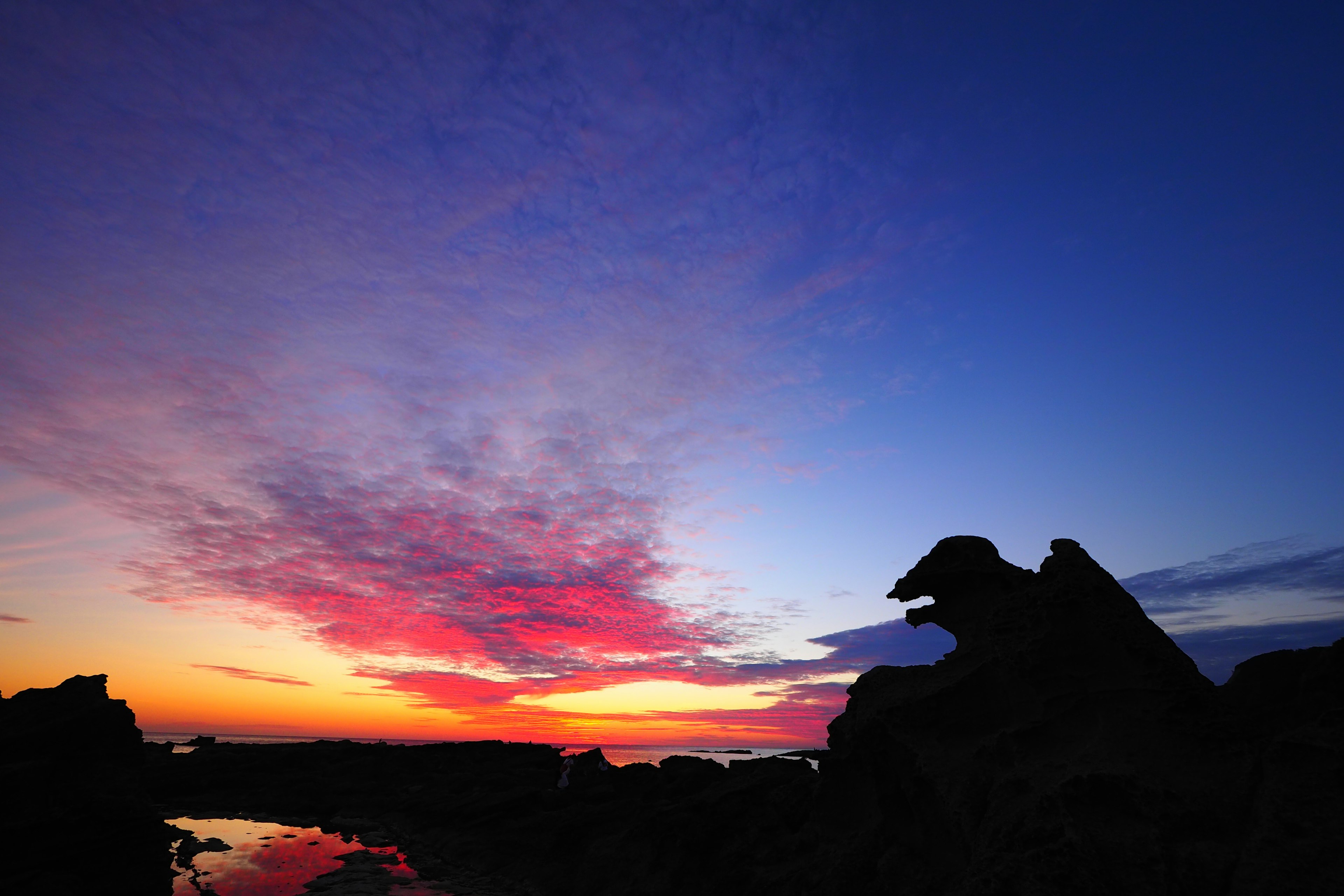 A stunning sunset with vibrant colors and silhouettes of rocks