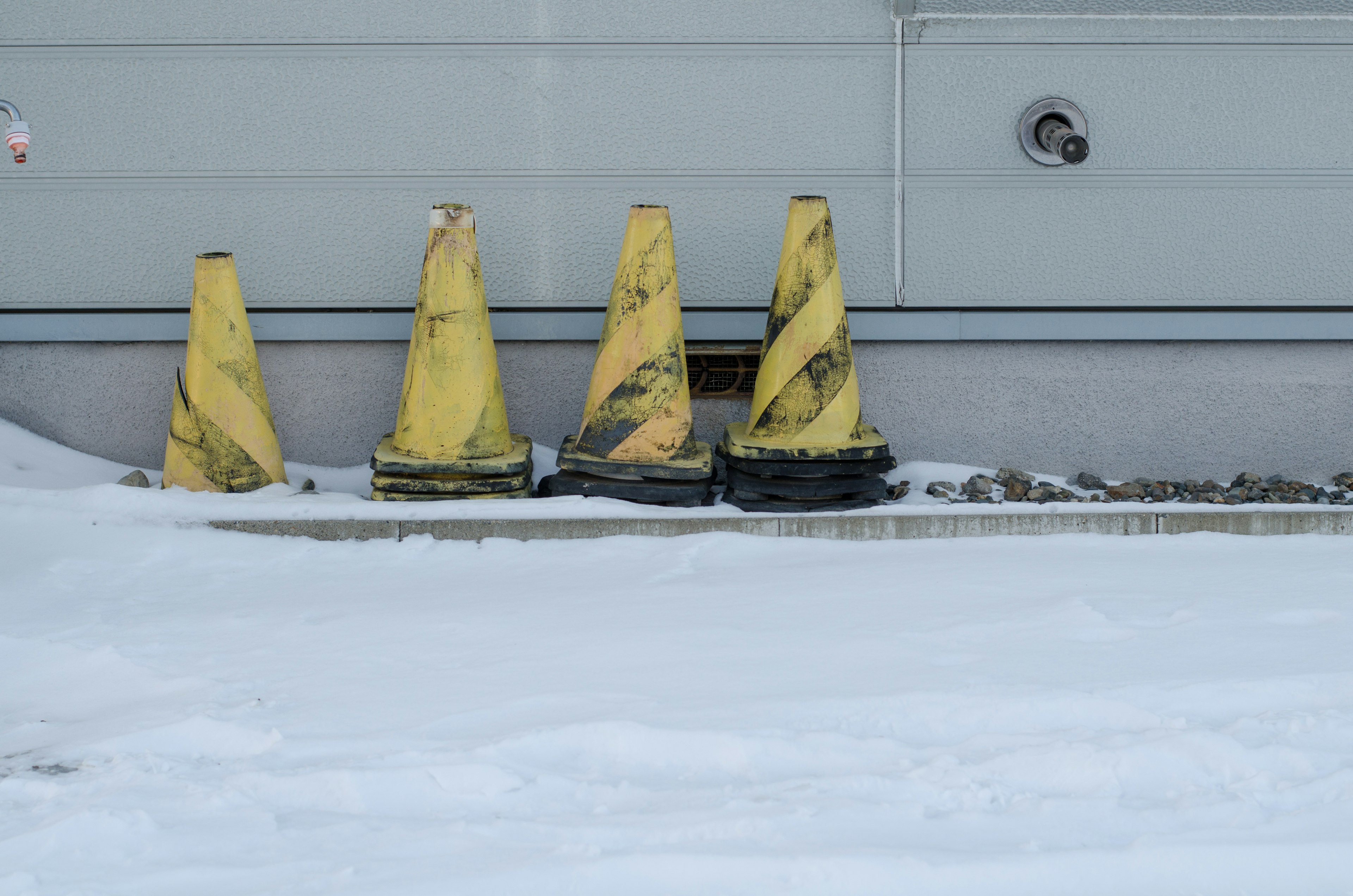 Eine Reihe gelber Verkehrshütchen auf schneebedecktem Boden