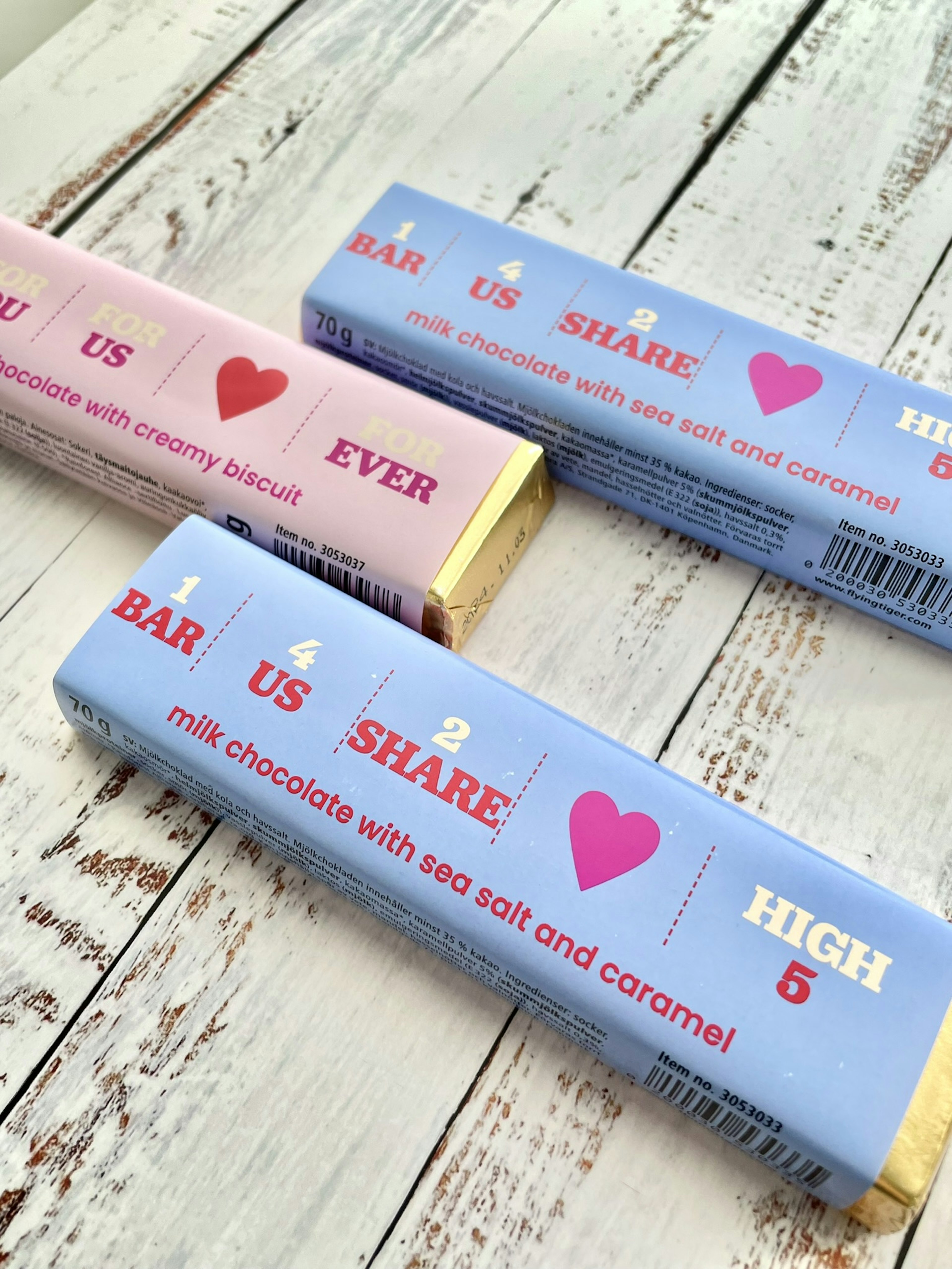 Kemasan batang cokelat yang dipajang dengan desain pink dan biru menampilkan teks yang playful