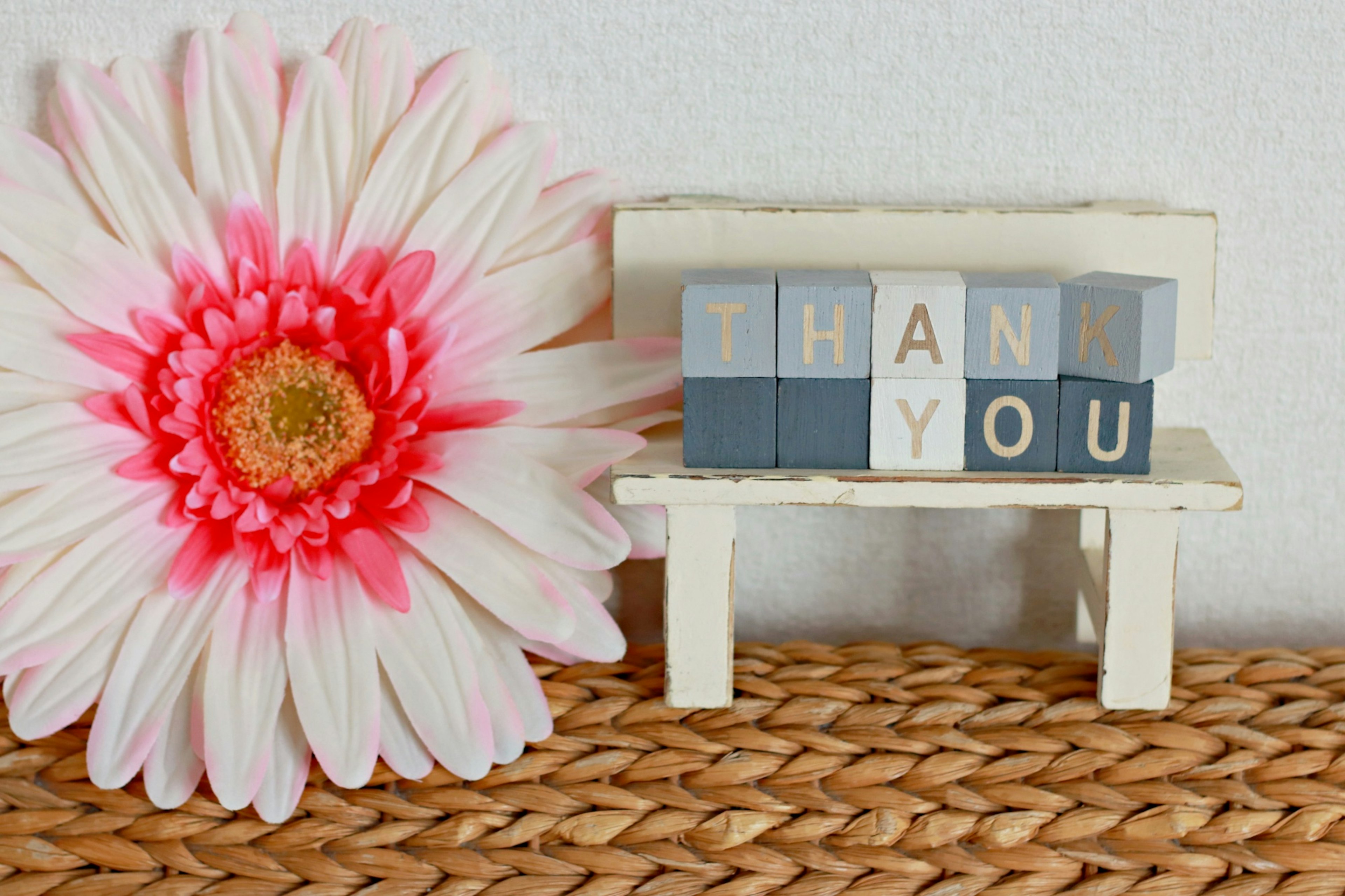 ピンクの花と木製の小さなベンチに置かれた「THANK YOU」の文字