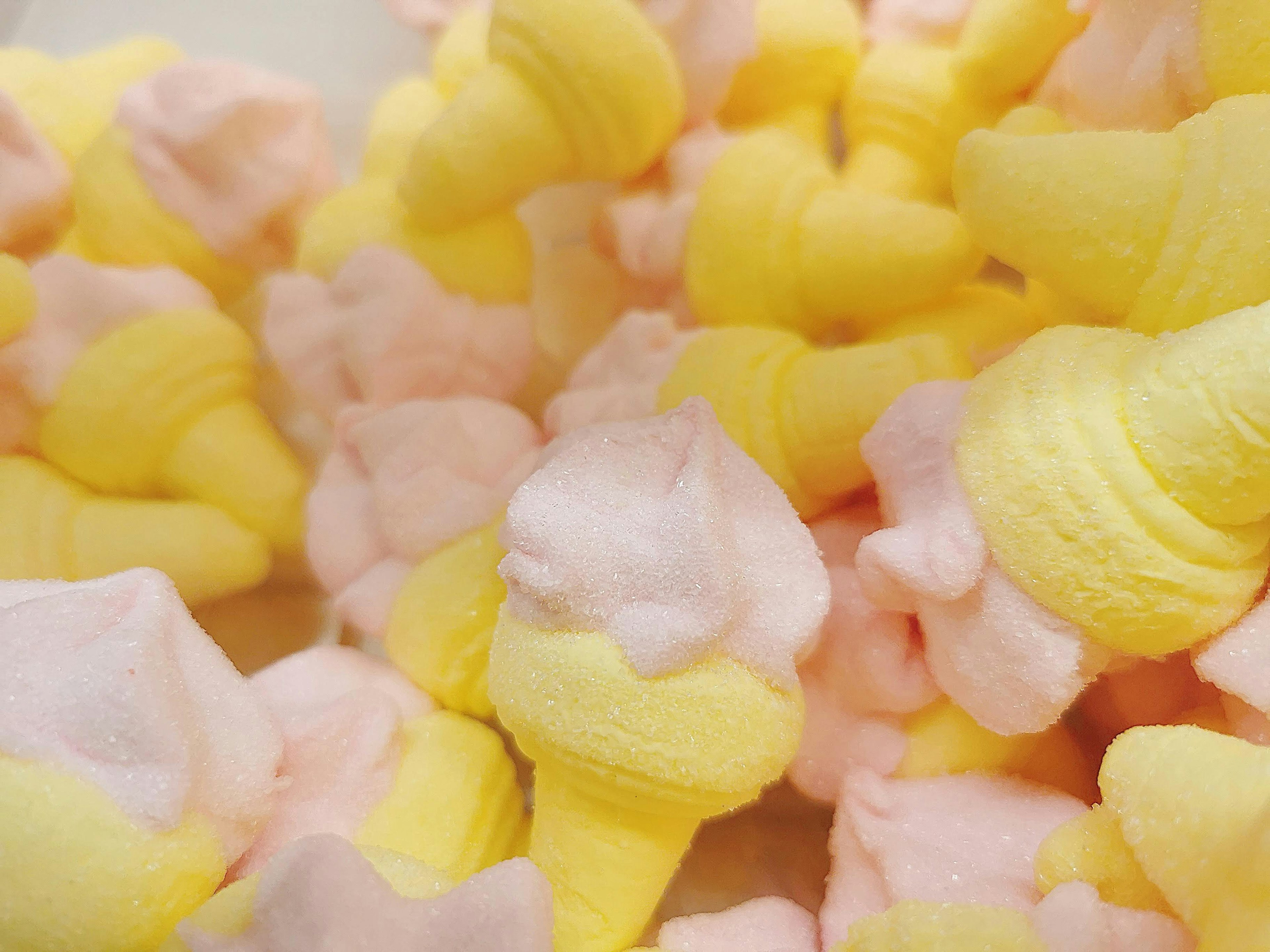 A close-up of colorful marshmallow ice cream cones in yellow and pink