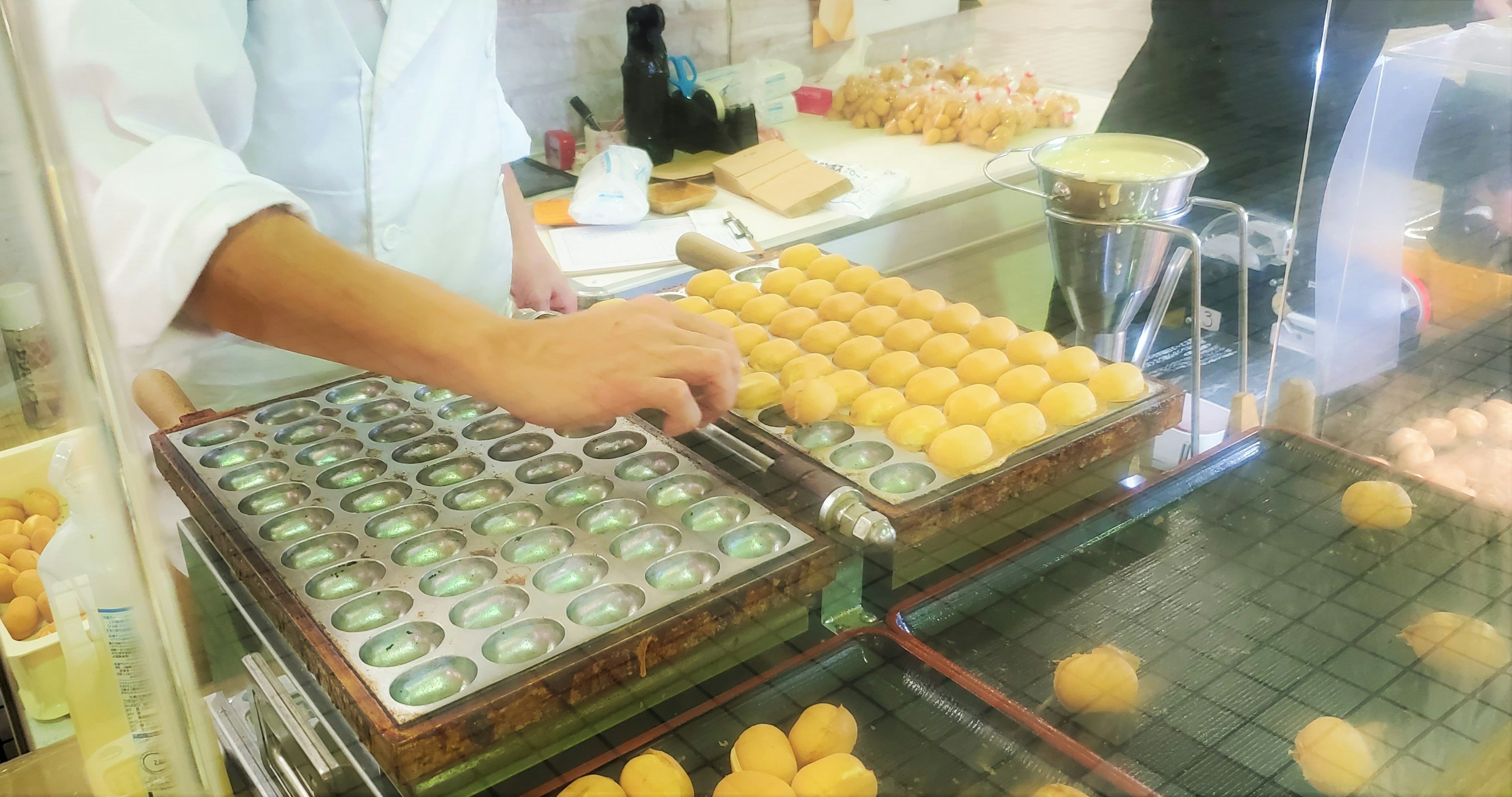 A chef preparing takoyaki using a traditional grill