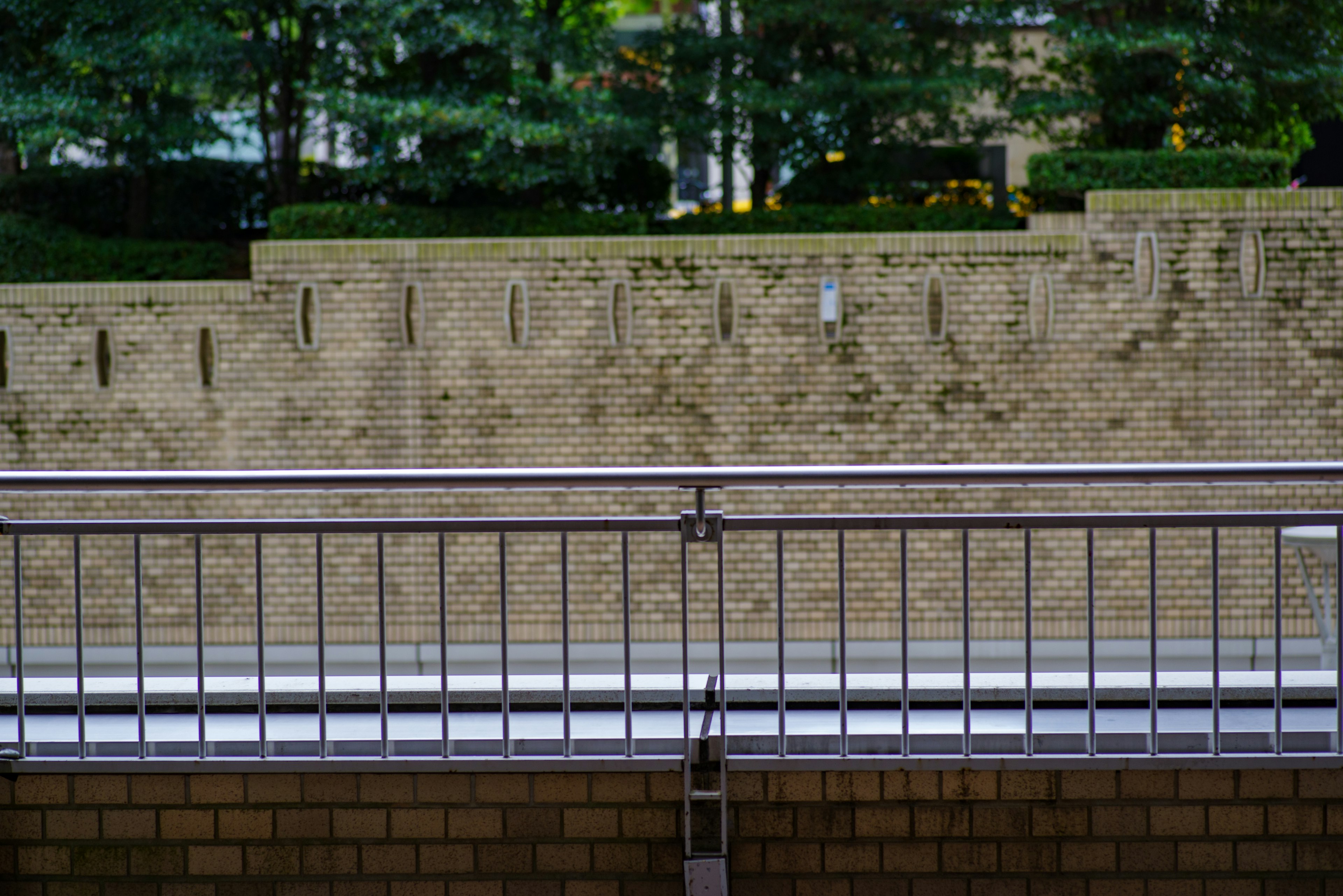 Metal railing with a stone wall and greenery in the background