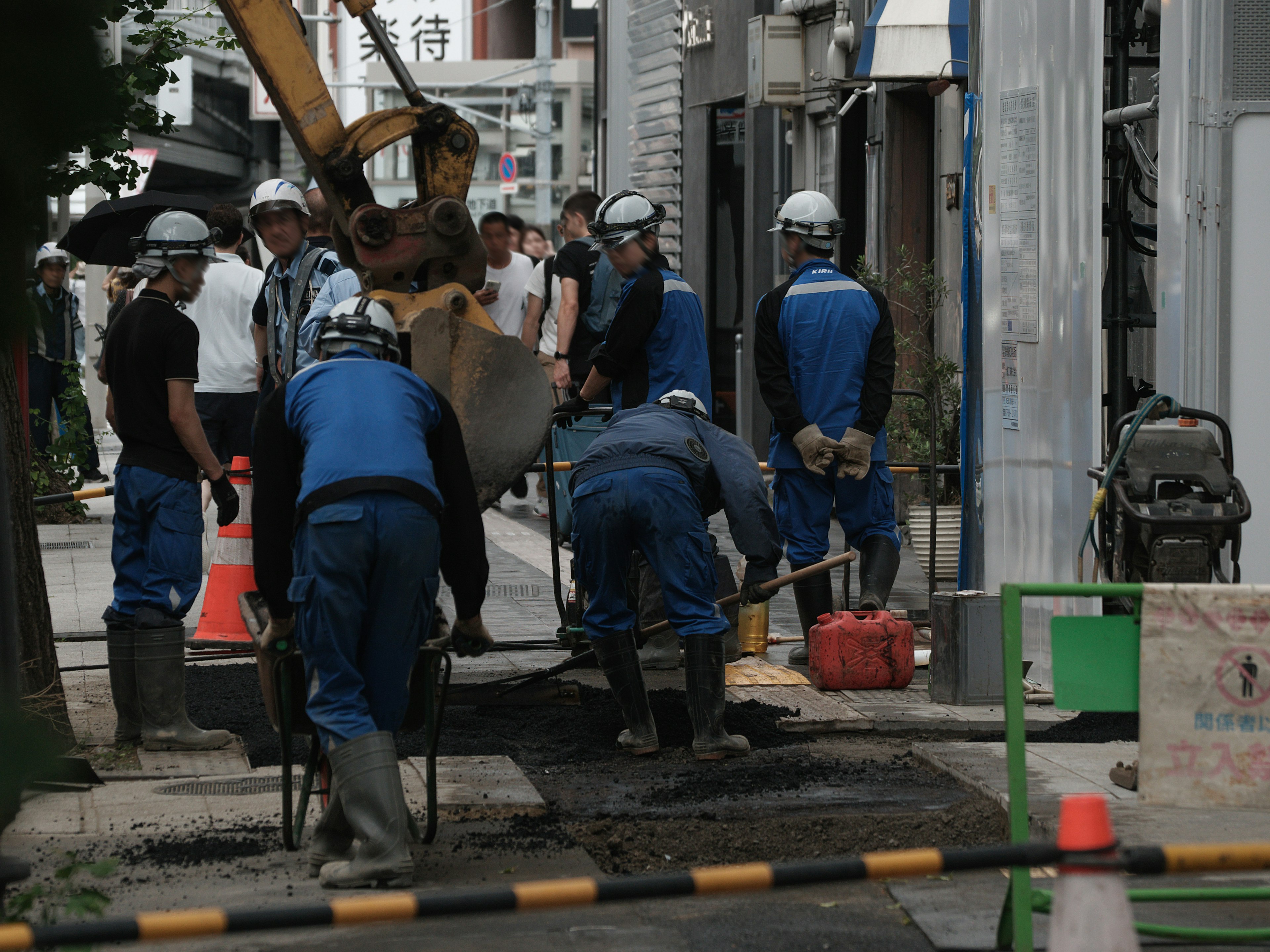 工事現場で作業する作業員たち、青い作業服を着用、重機が背景に見える