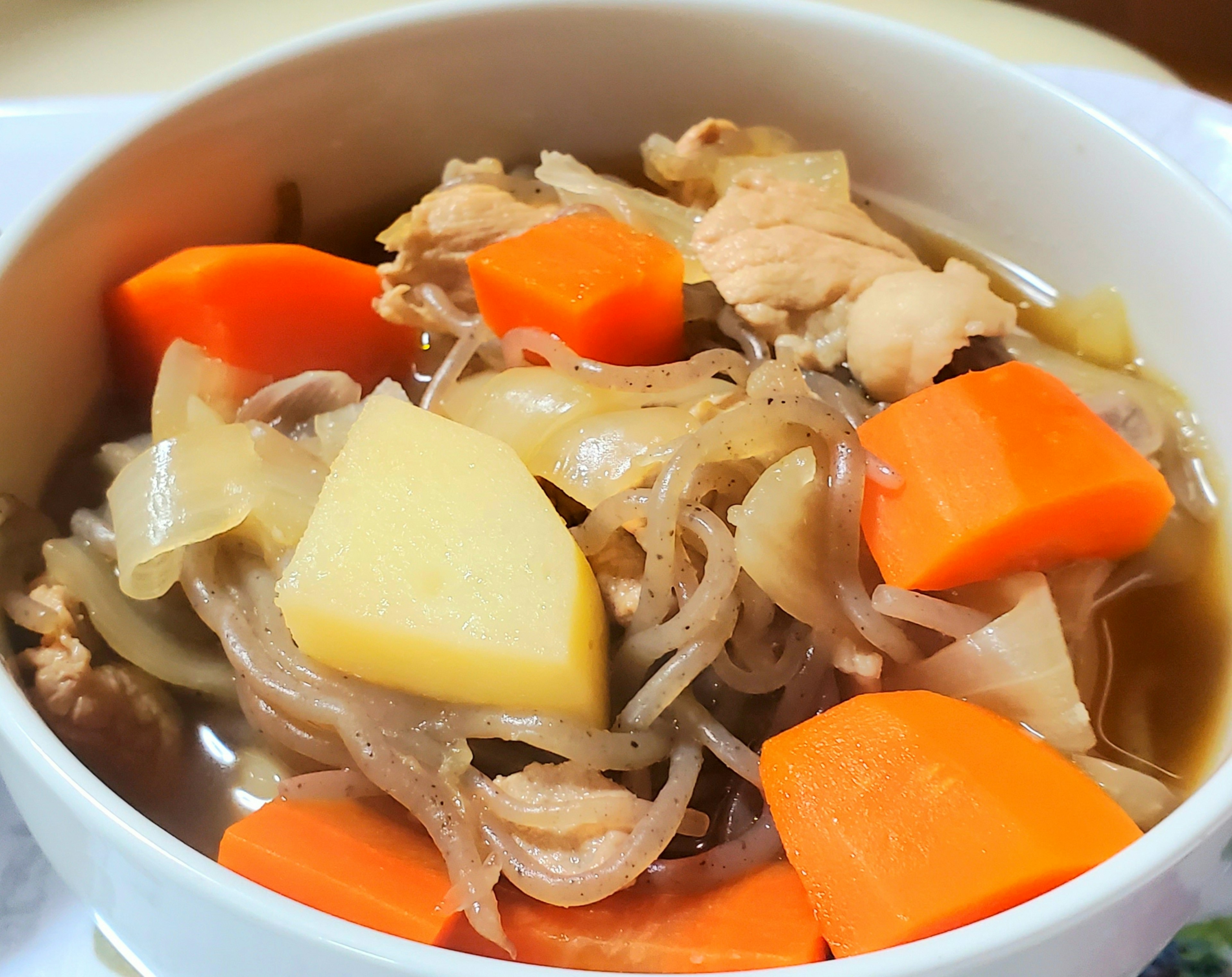 Mangkuk putih penuh dengan sup ayam dan sayuran