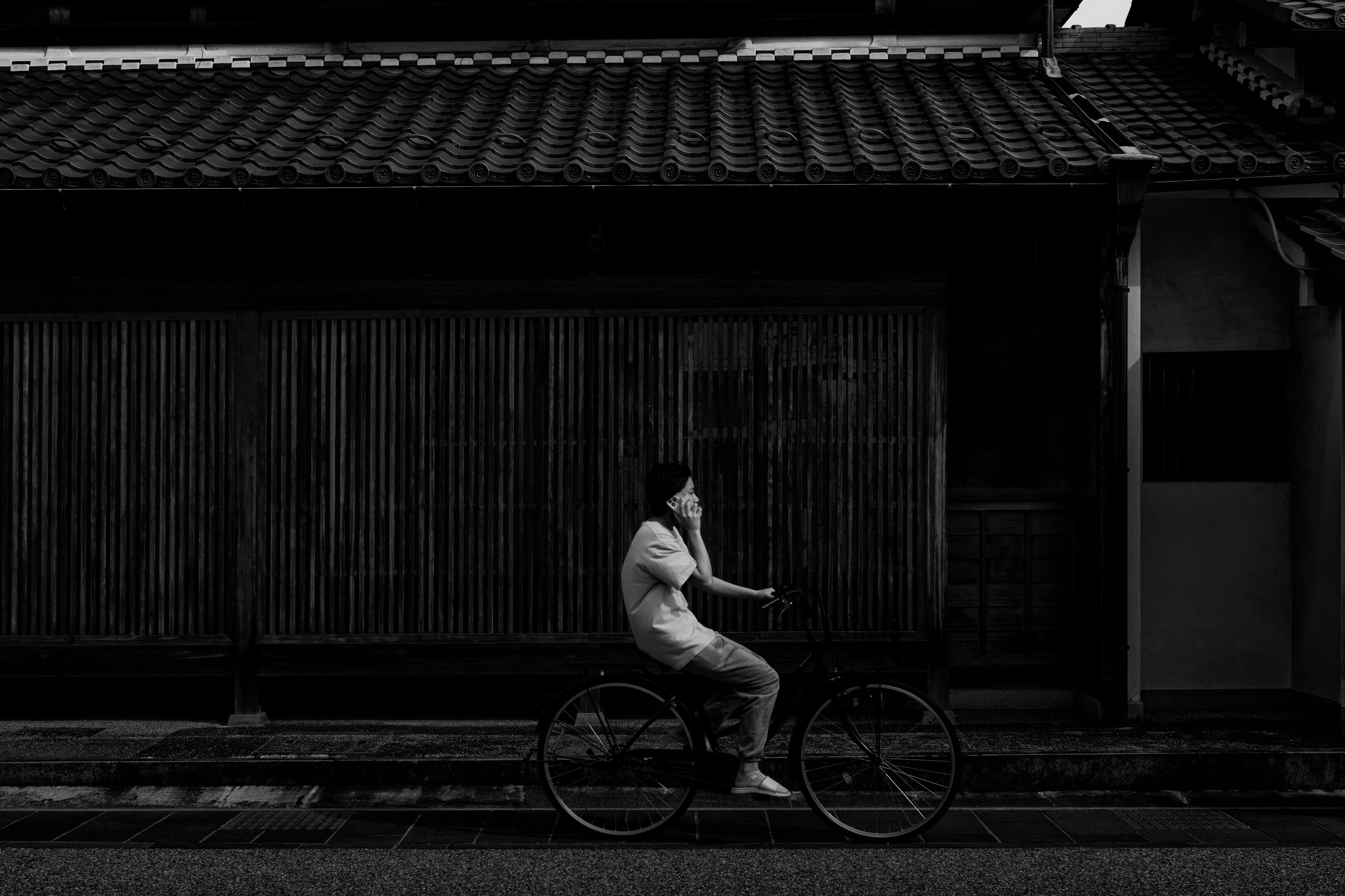 白黒の自転車に乗る人物と伝統的な日本の建物の背景