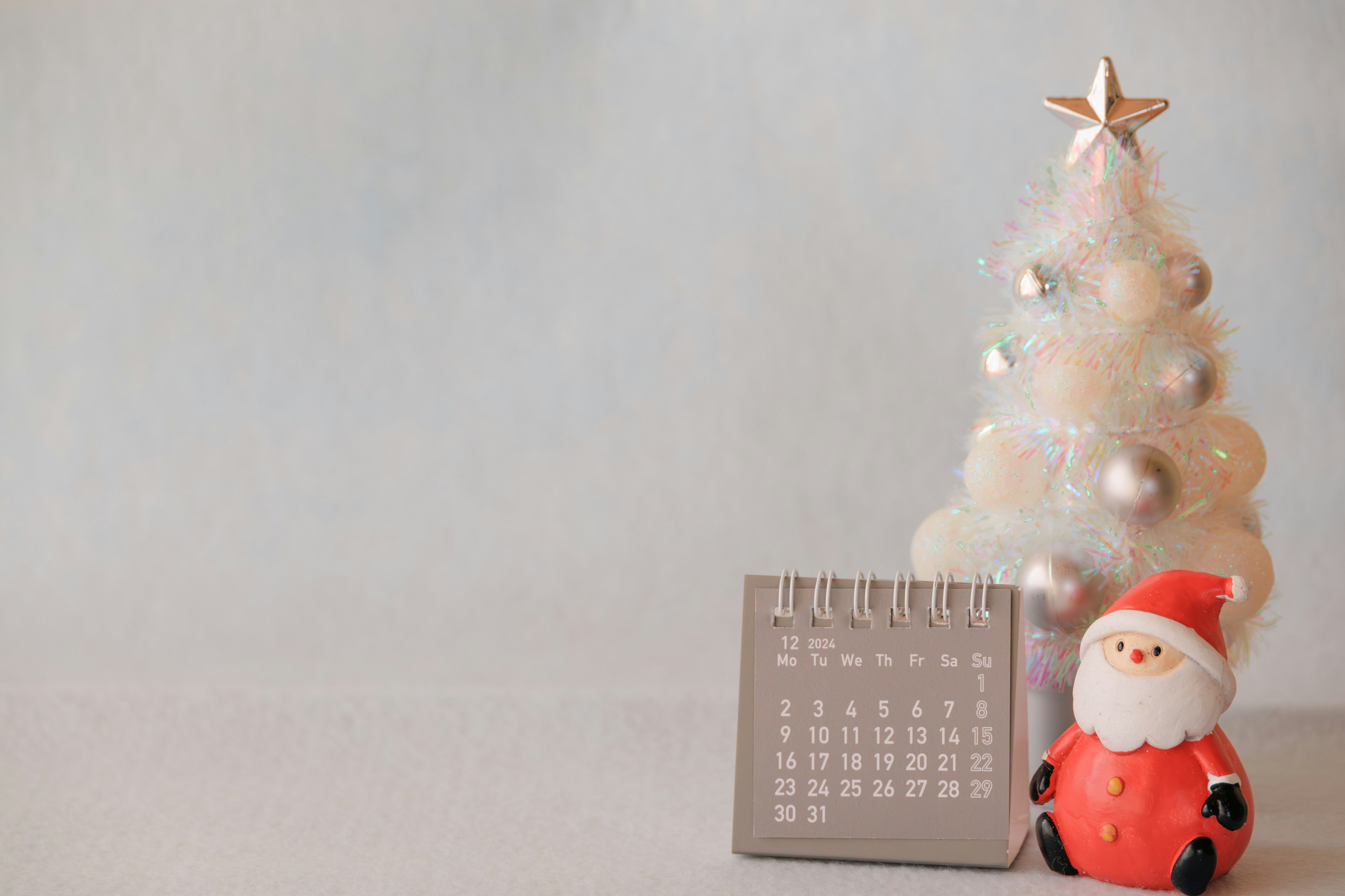 A calendar next to a Christmas tree and a Santa figurine