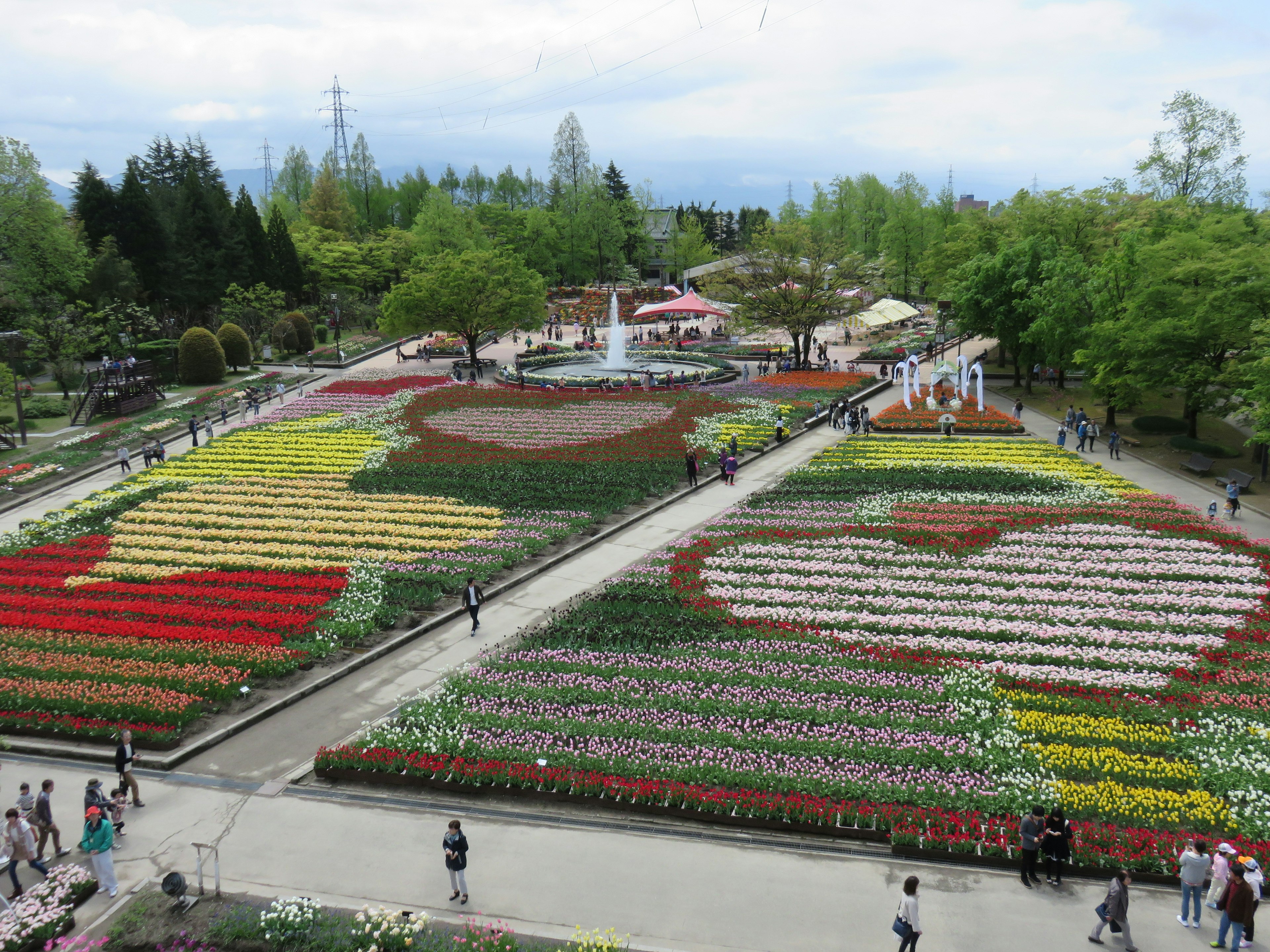 Un hermoso paisaje de parque con un jardín de flores colorido y parterres de flores con patrones Personas caminando por la zona