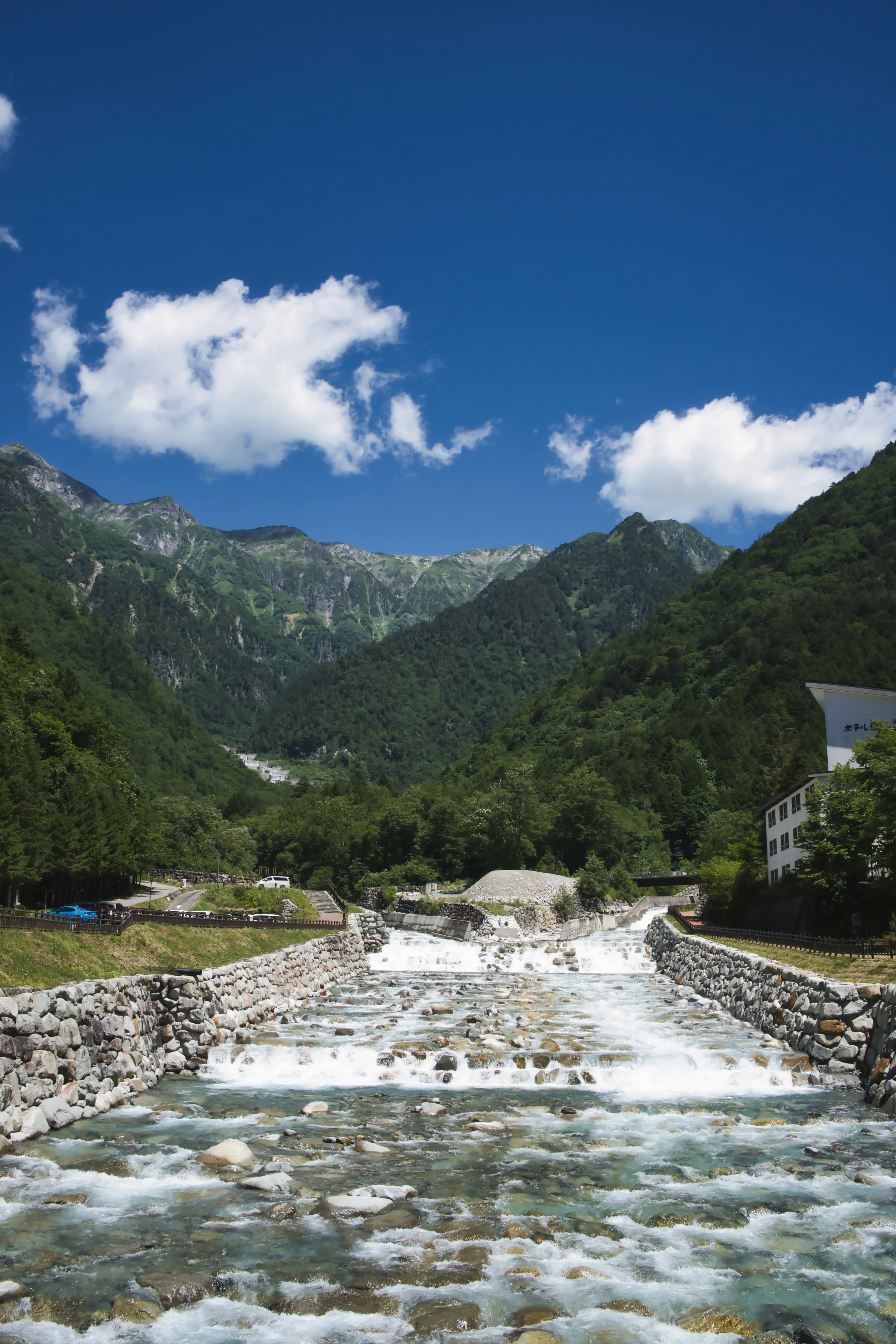 青い空と白い雲の下に流れる川と山々の風景