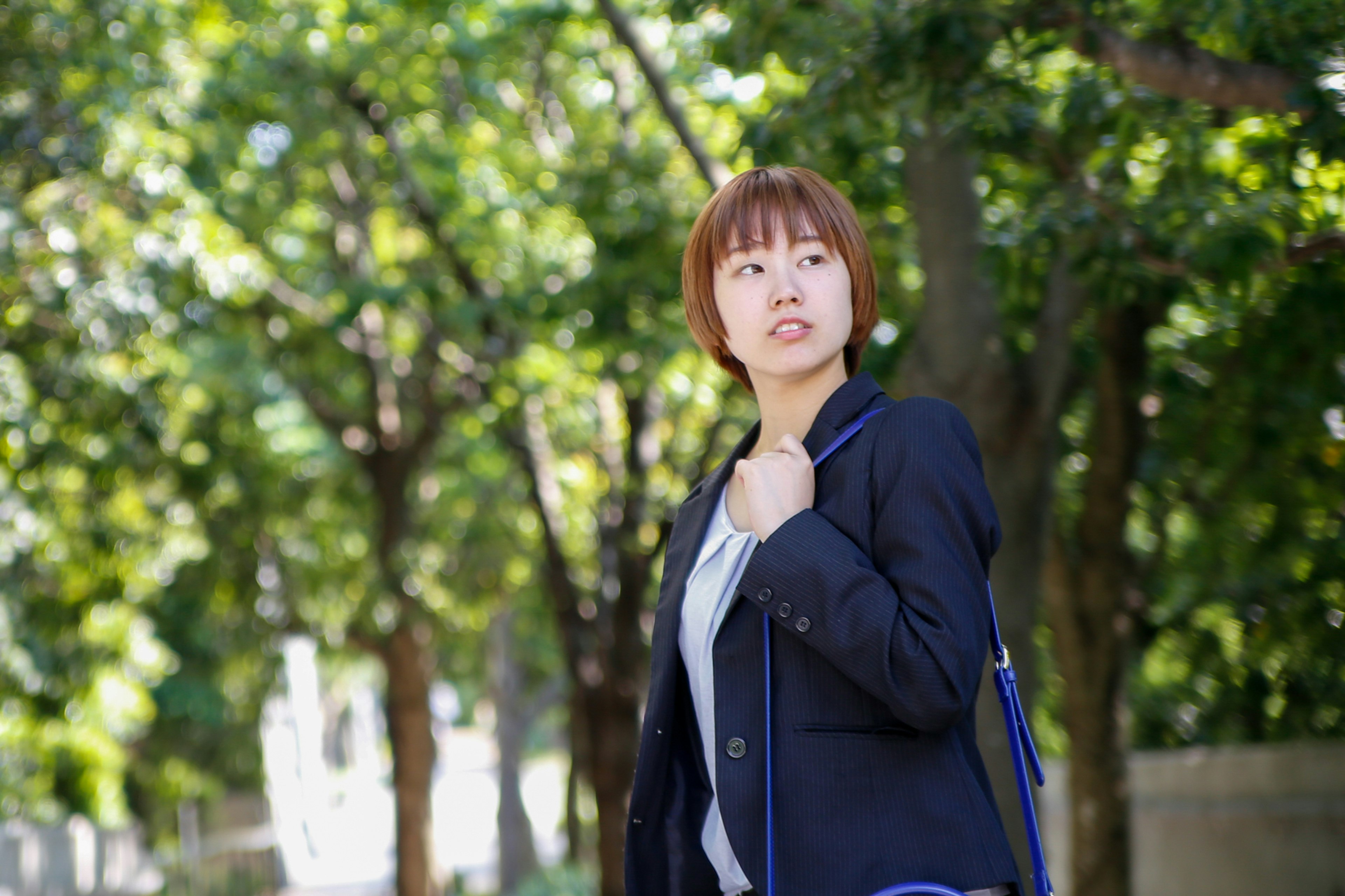 A woman walking among green trees