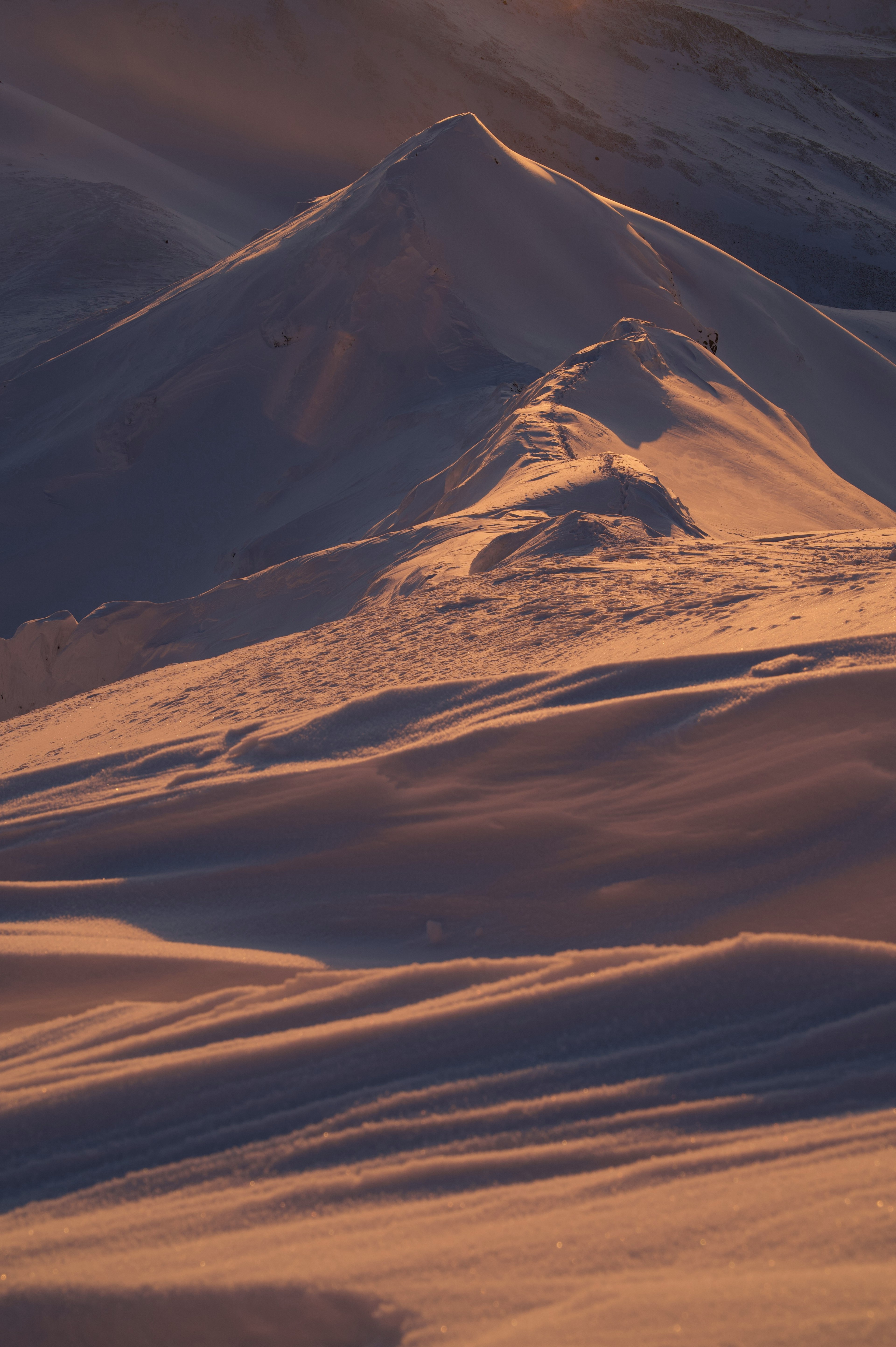 Un hermoso paisaje de una montaña cubierta de nieve la luz del atardecer iluminando la cima