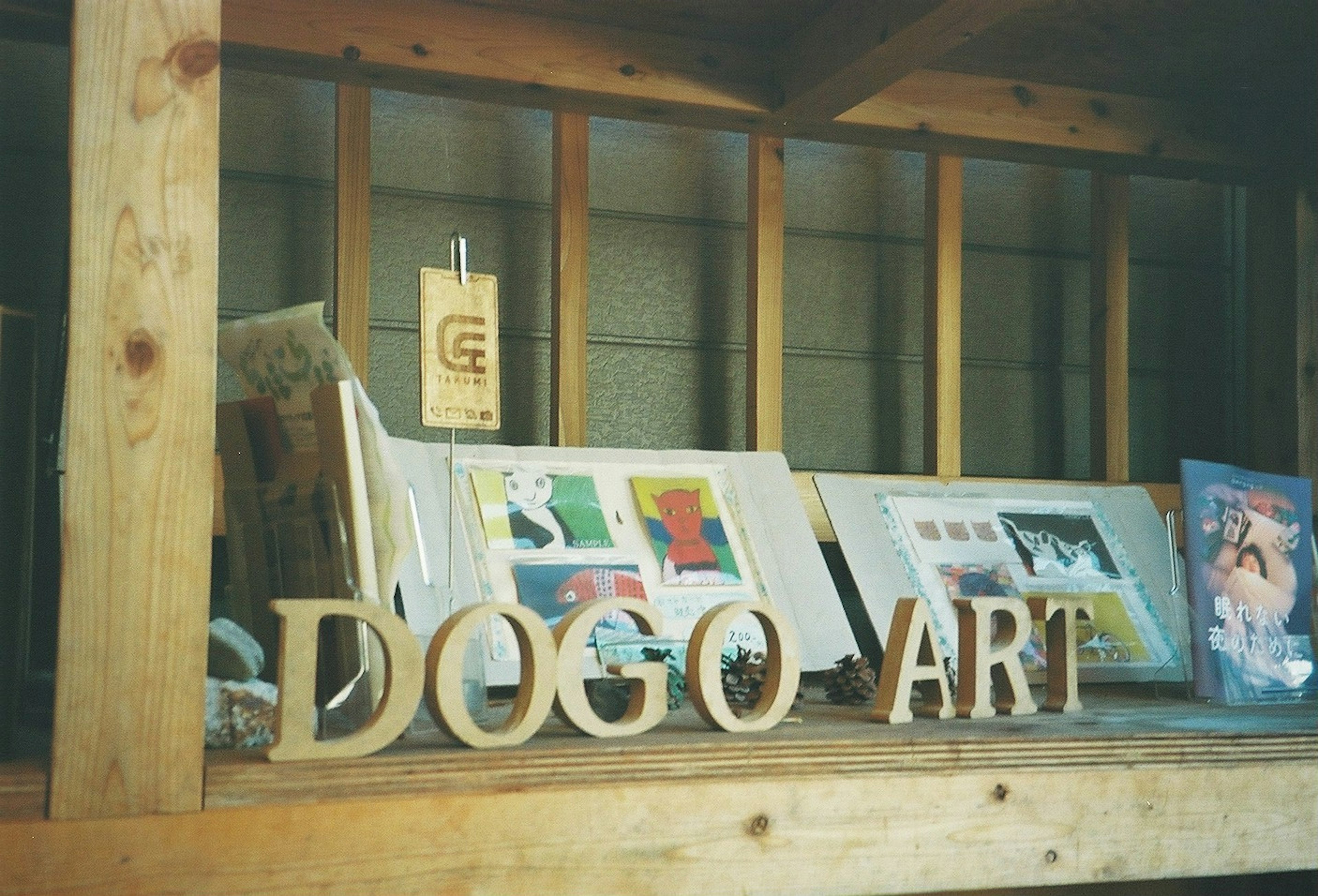 Wooden shelf displaying the words DOGO ART and colorful art pieces