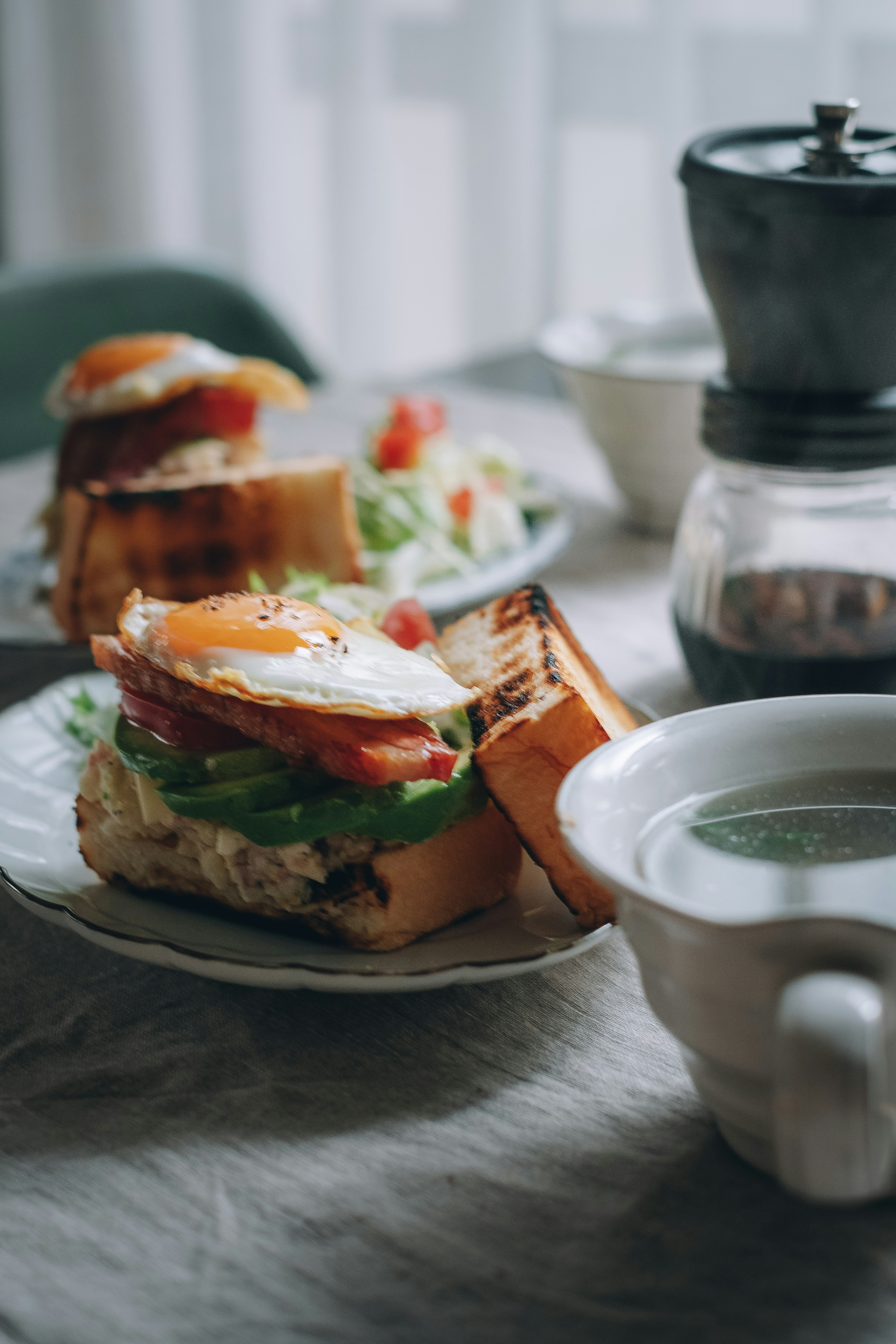 Assiette de petit-déjeuner avec des sandwichs aux œufs et une salade accompagnée de café et de thé vert