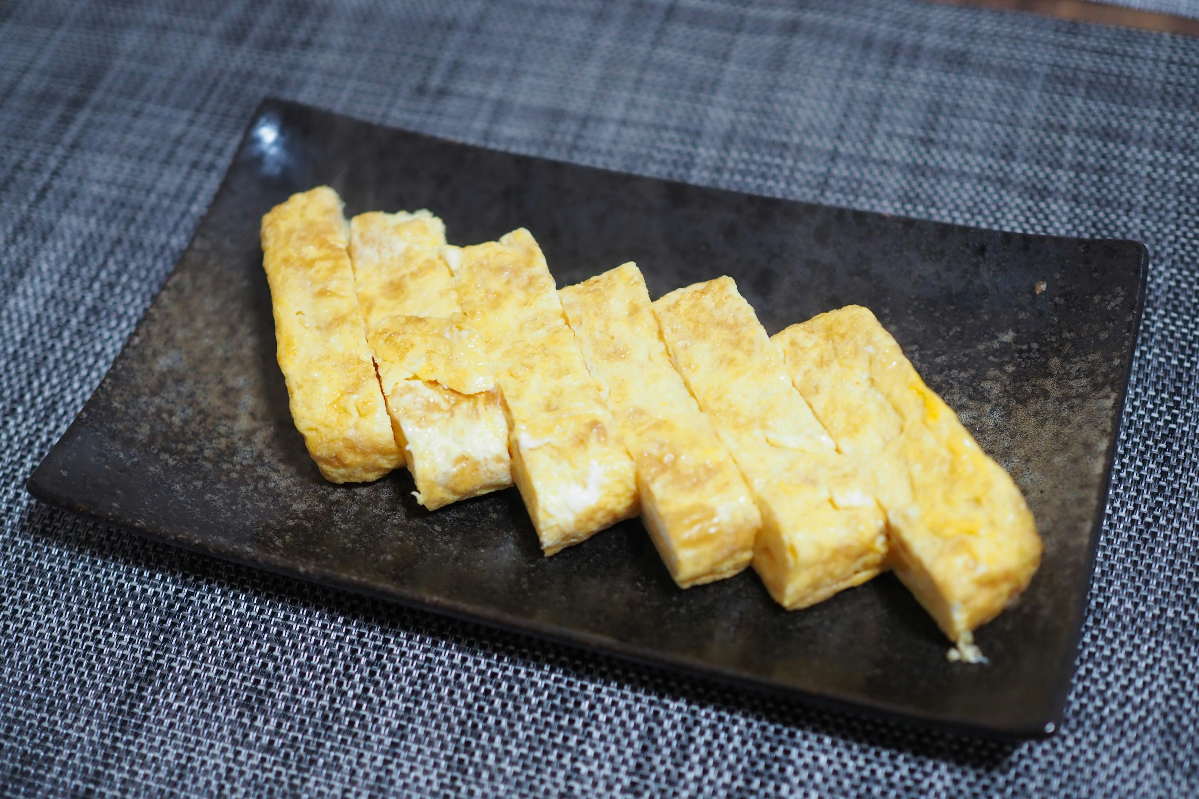 Tortilla de huevo en rodajas sobre un plato negro