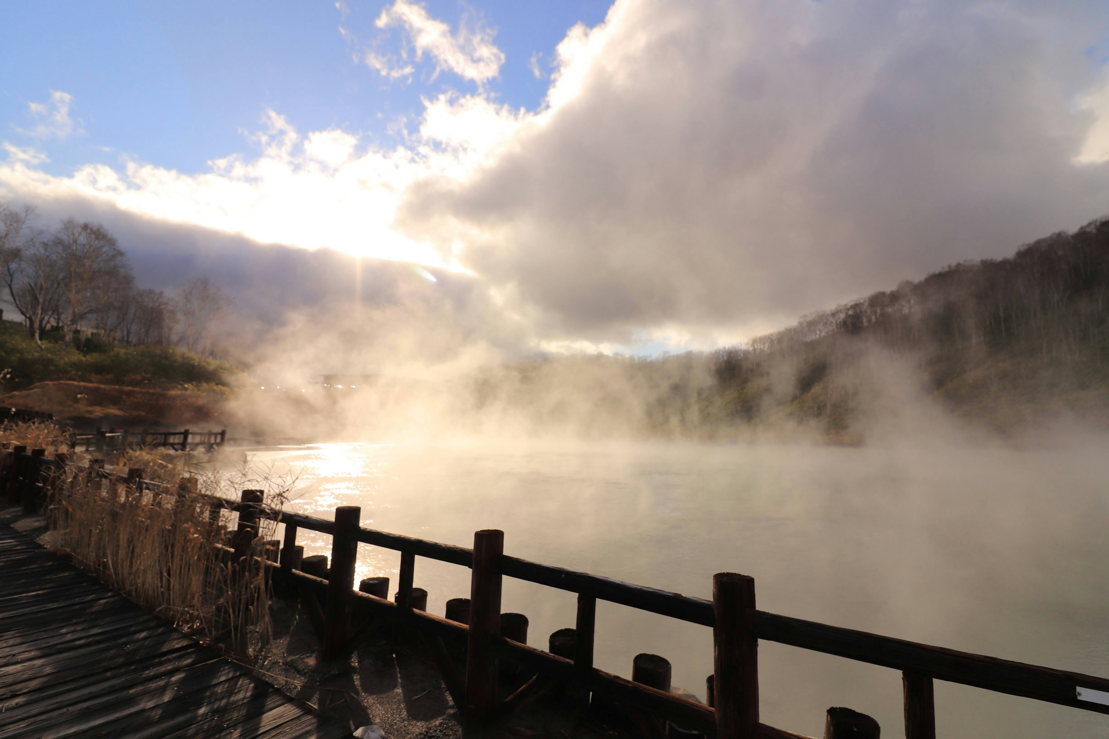 Scenic view of a lake with rising steam and a wooden railing