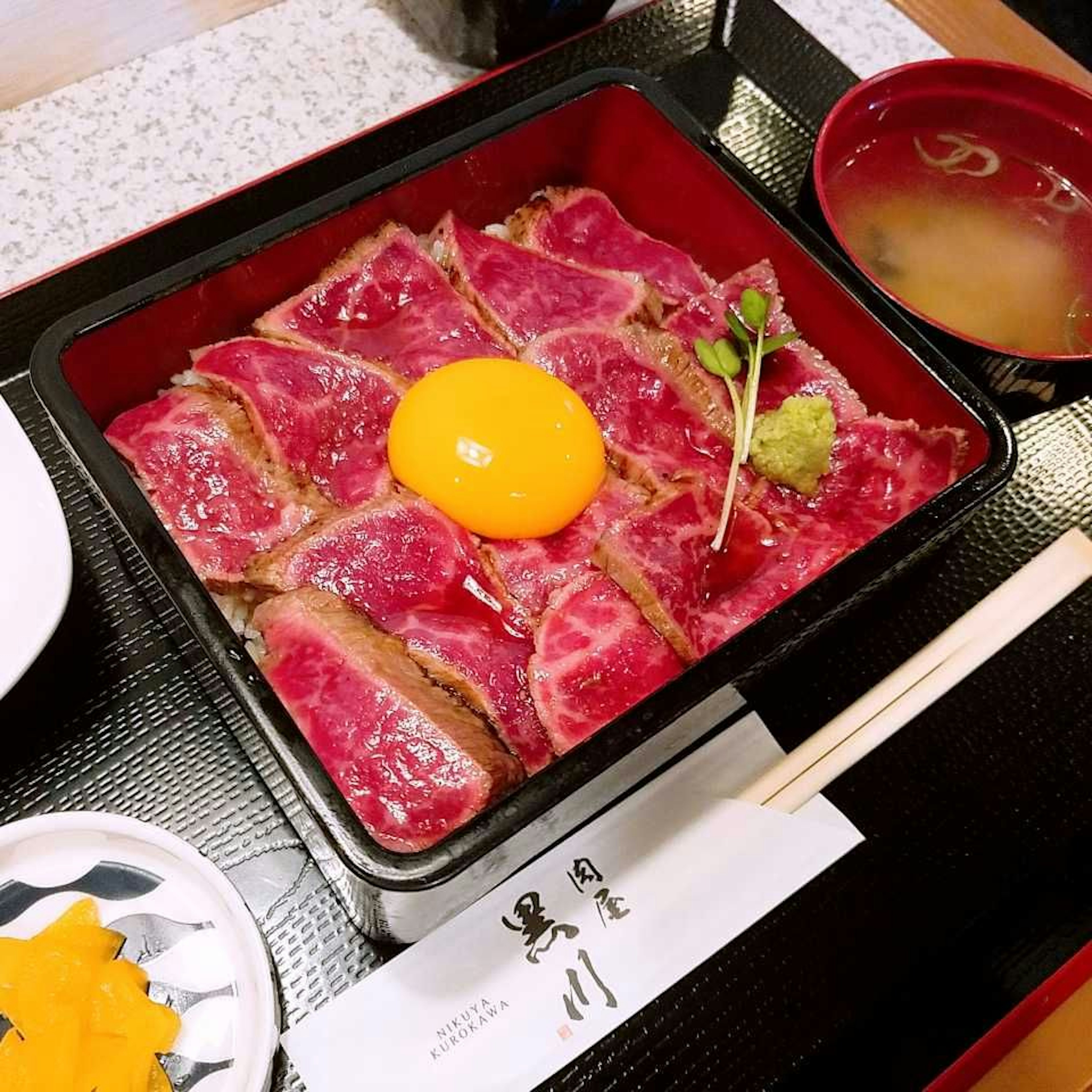 Sliced wagyu beef with a raw egg and wasabi served in a traditional box