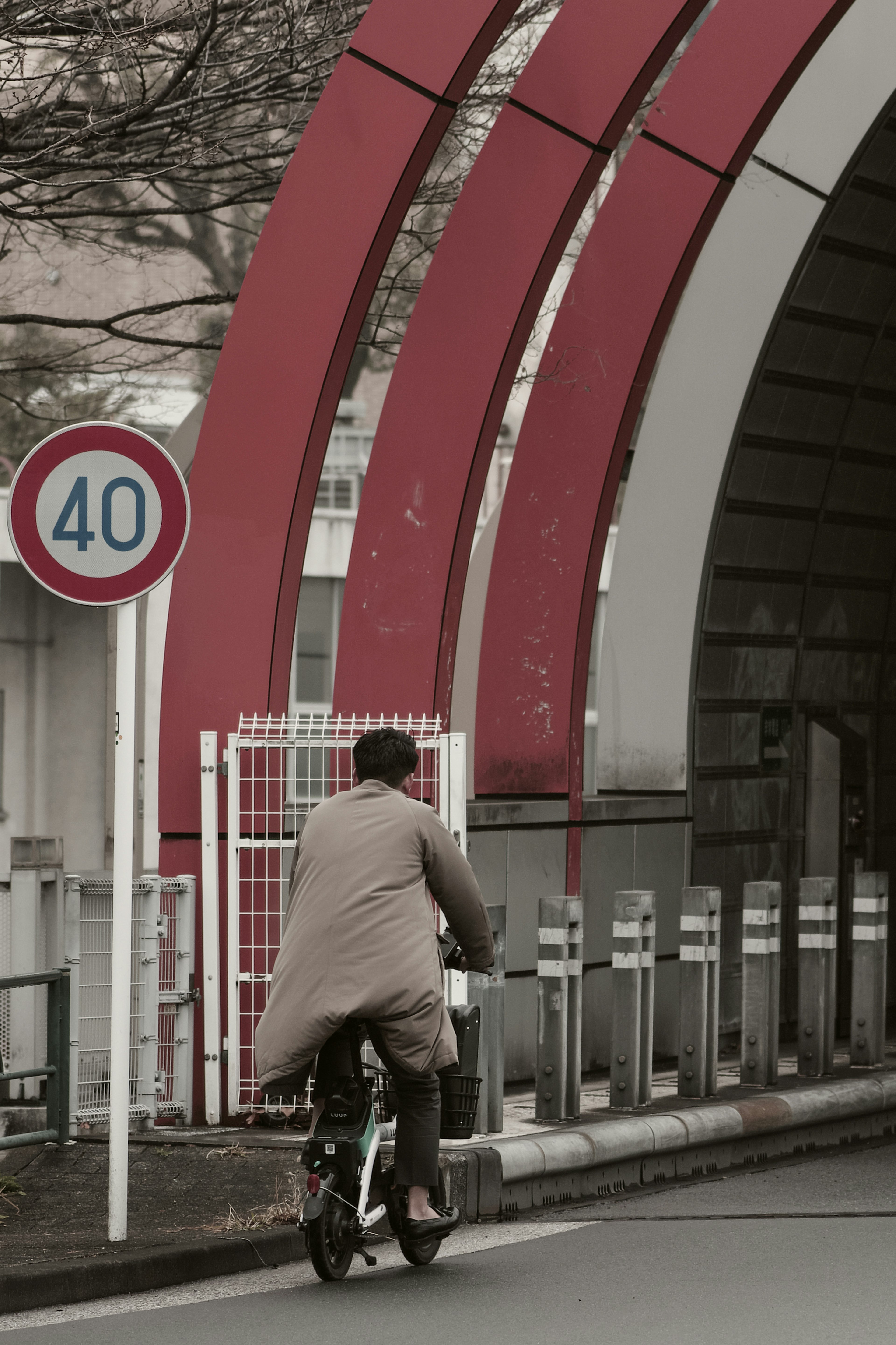 Un hombre montando en bicicleta bajo un túnel con arcos rojos