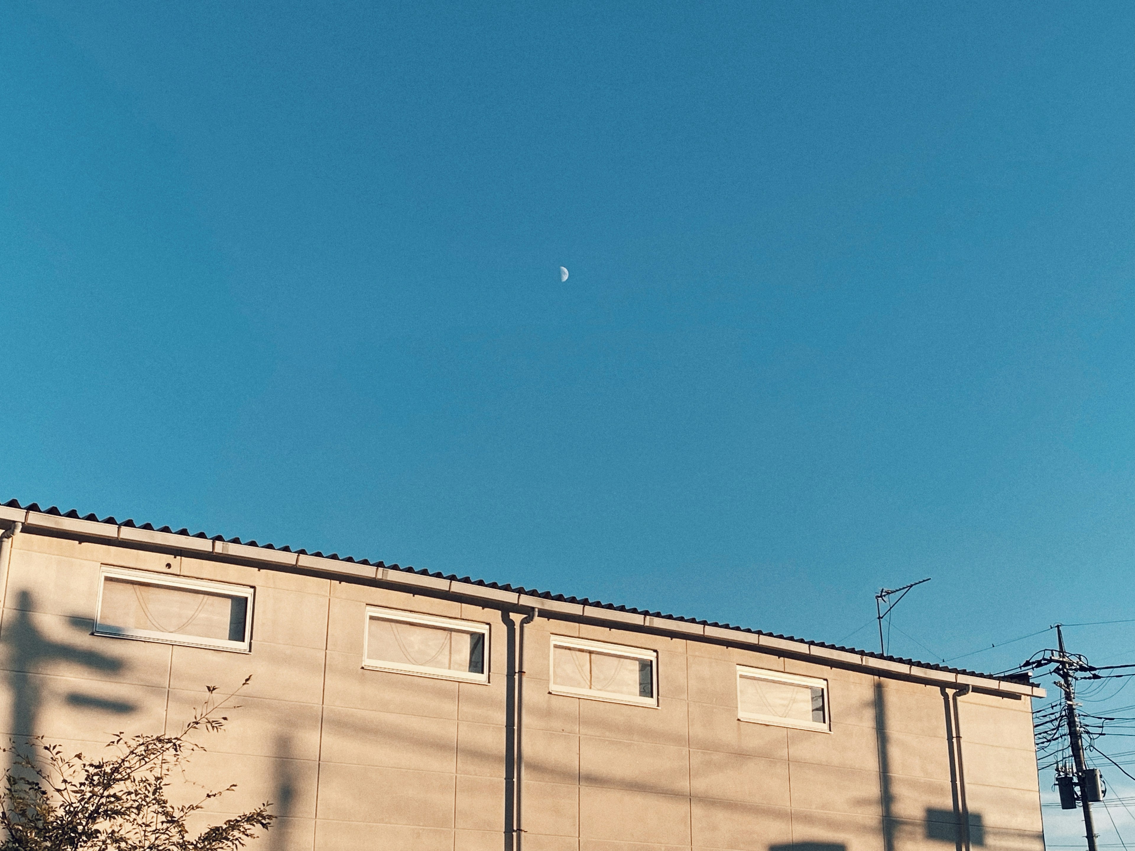 Silhouette eines Gebäudes vor einem klaren blauen Himmel mit sichtbarem Mond