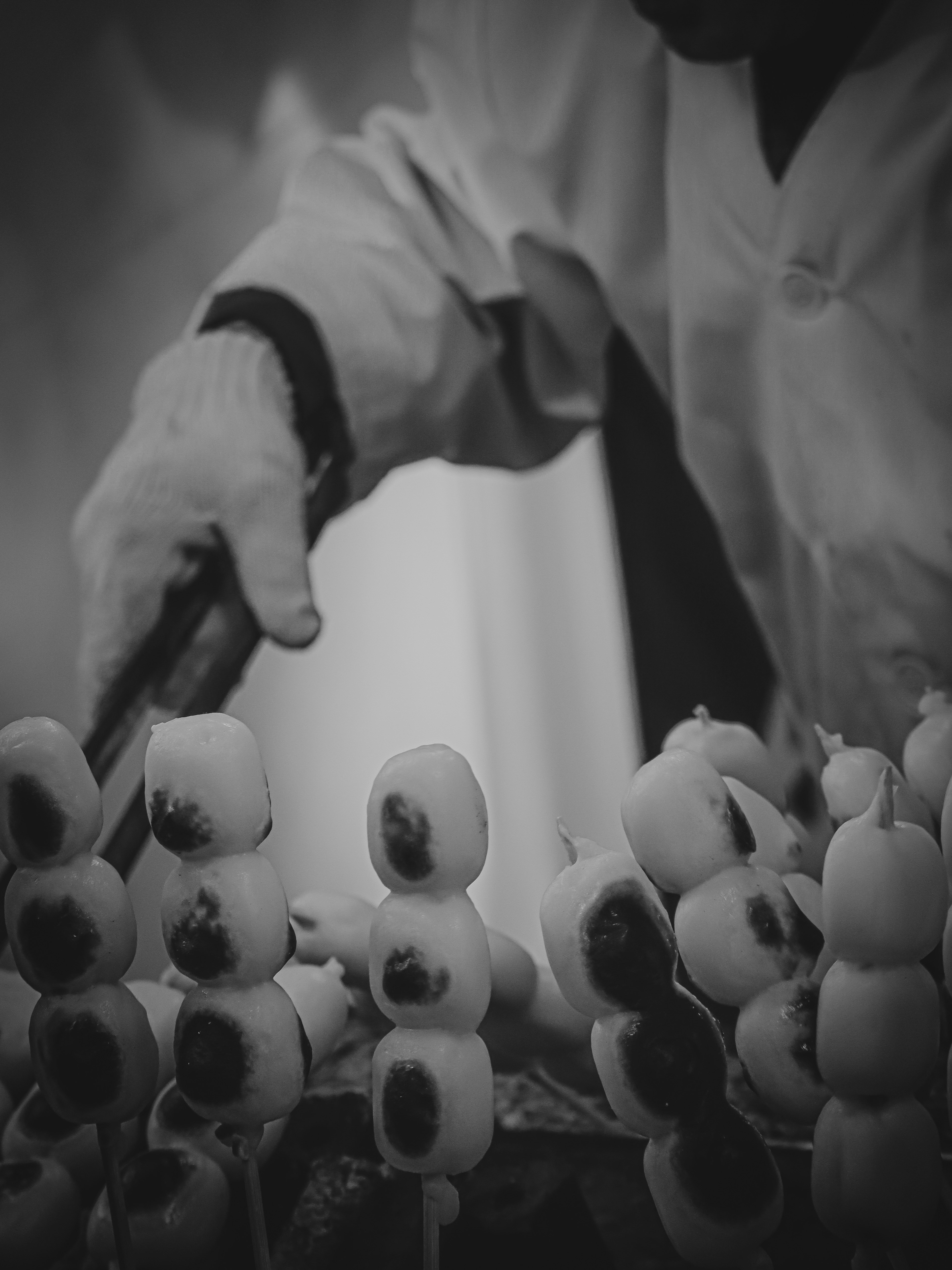 Black and white photo of a hand preparing skewered food