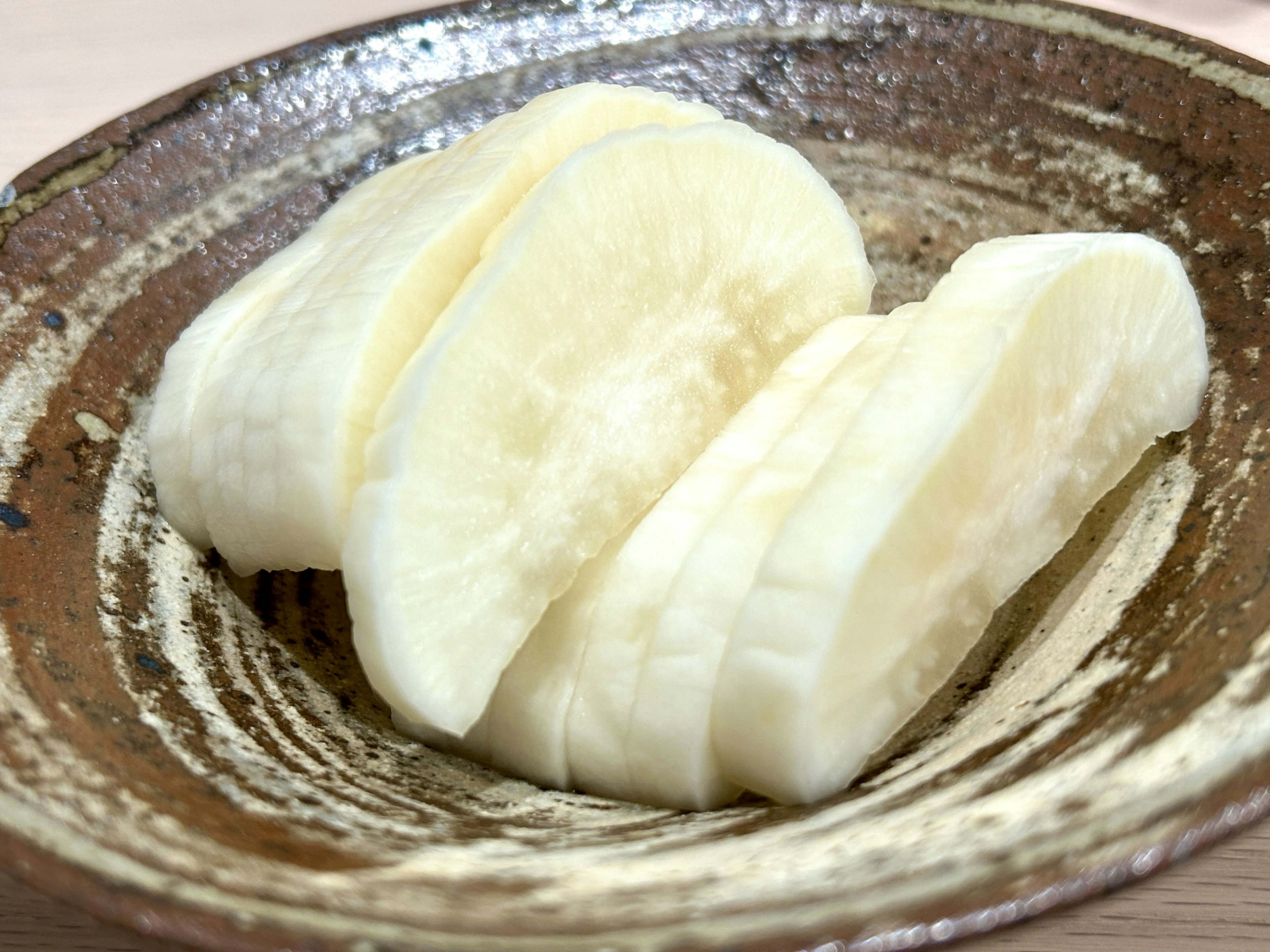 Fette di daikon servite su un piatto marrone