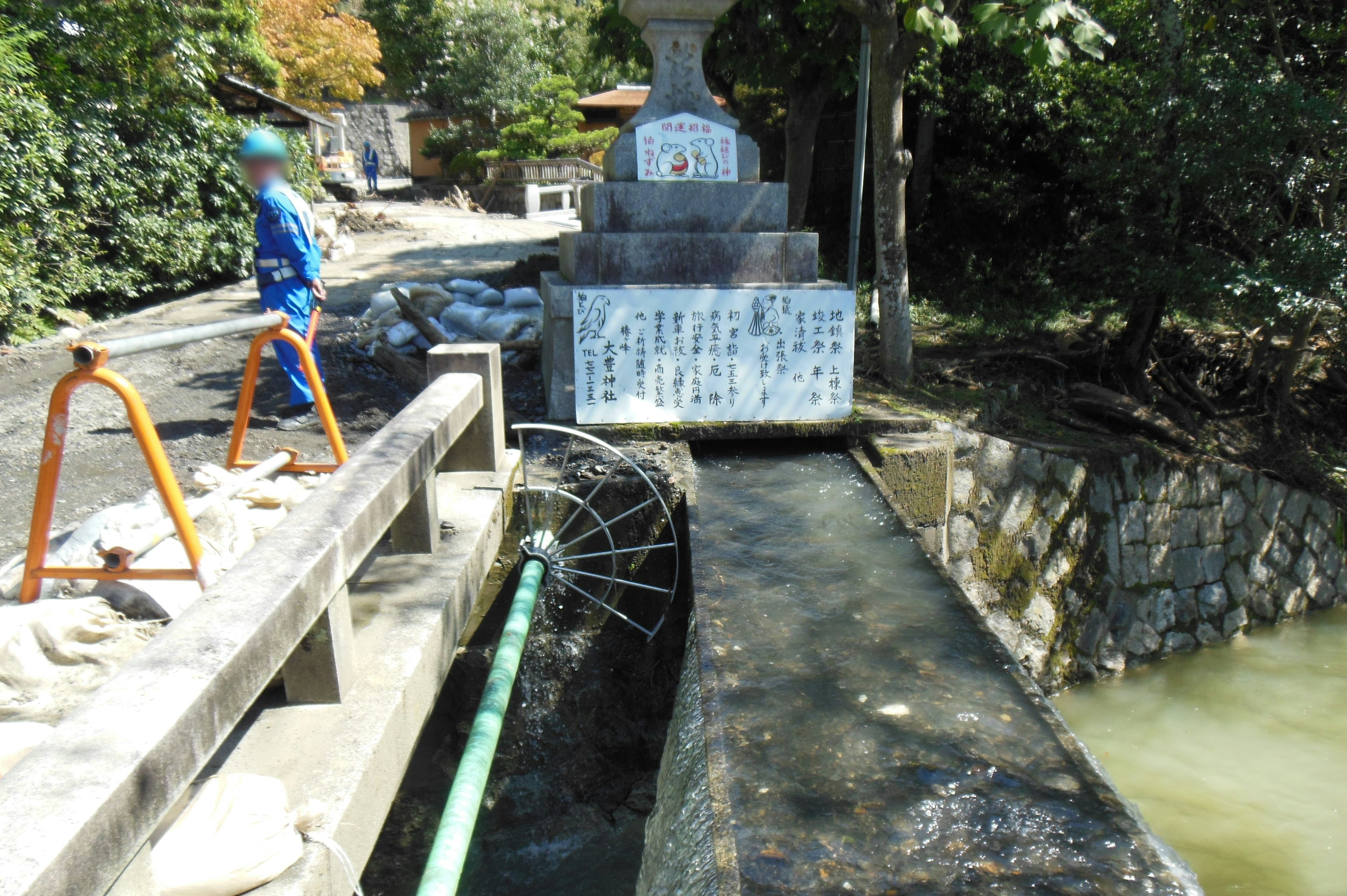 水路と石碑がある風景で作業する人