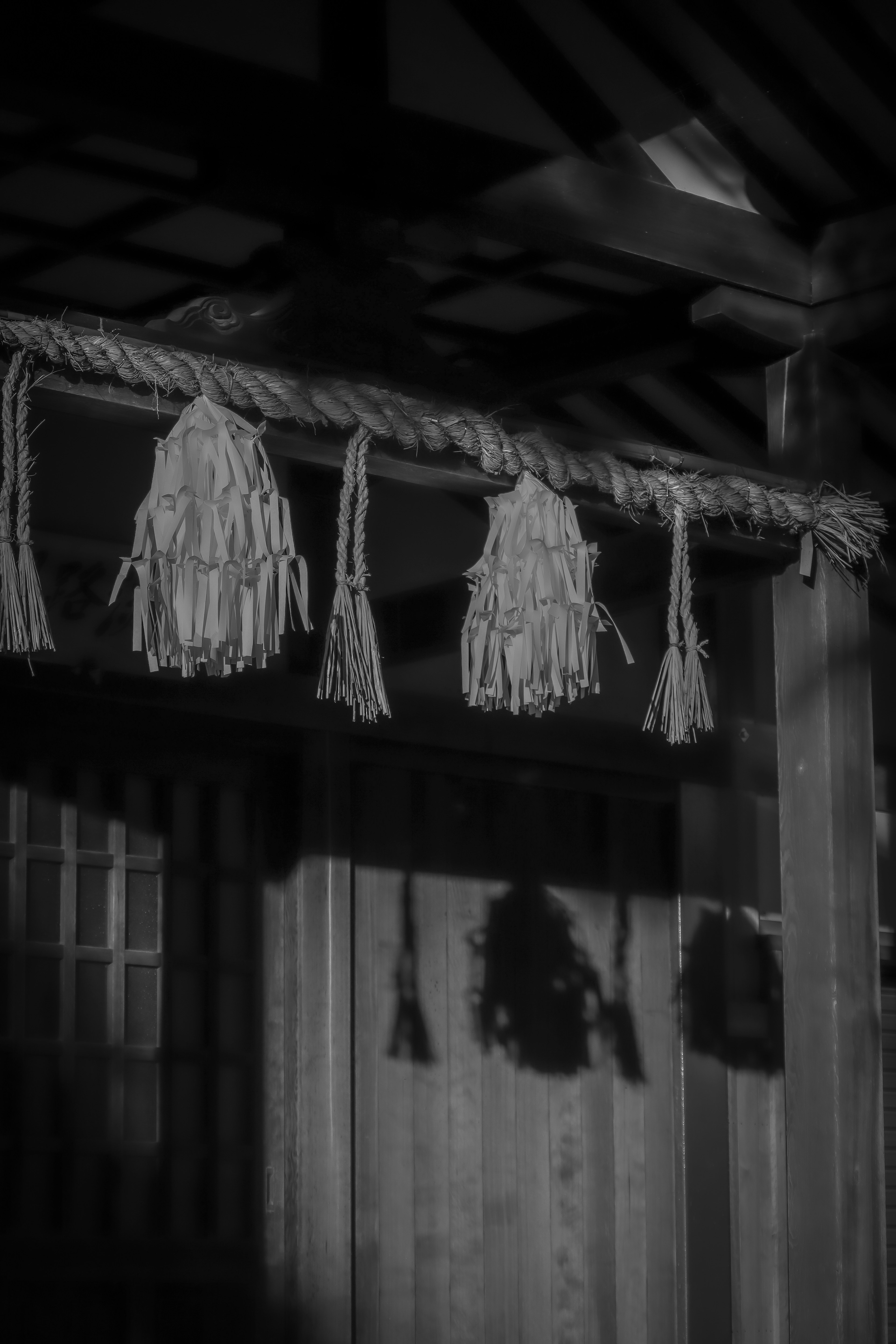 Objetos decorativos japoneses tradicionales colgando contra un fondo oscuro con sombras