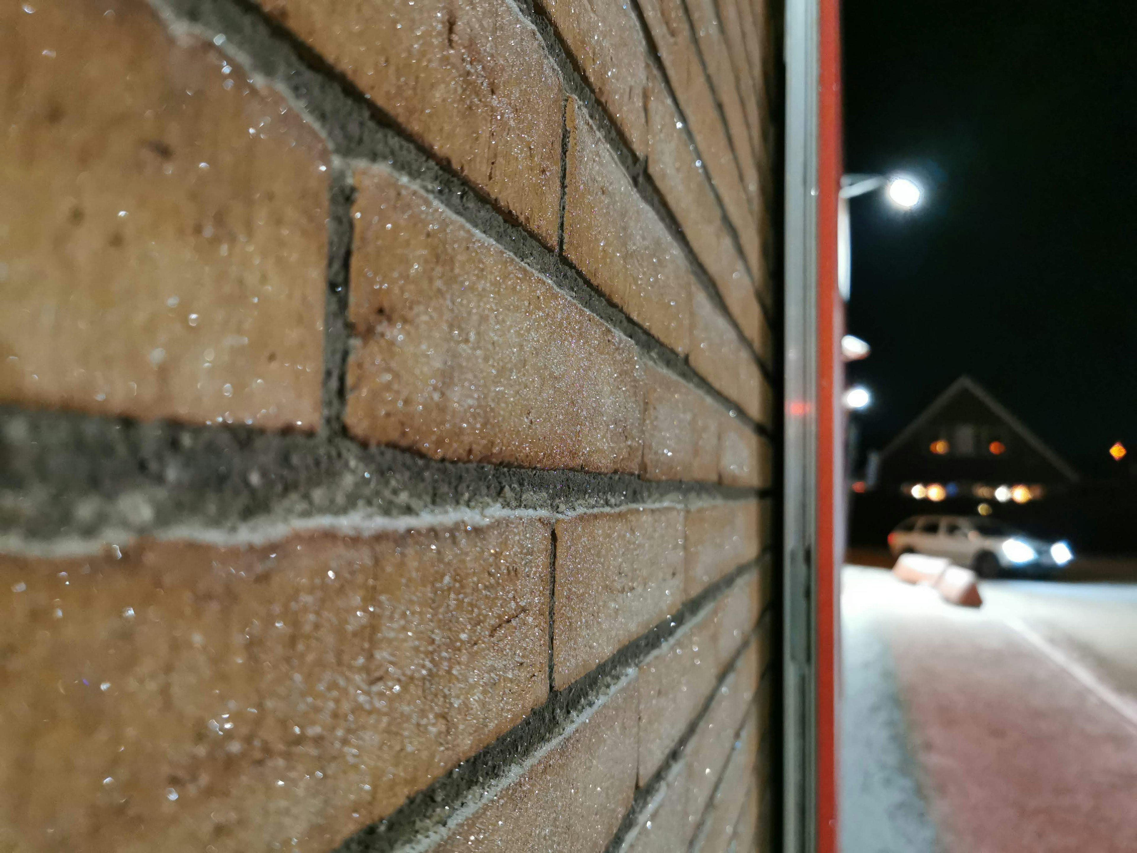 Primo piano di un muro di mattoni di notte con lampioni