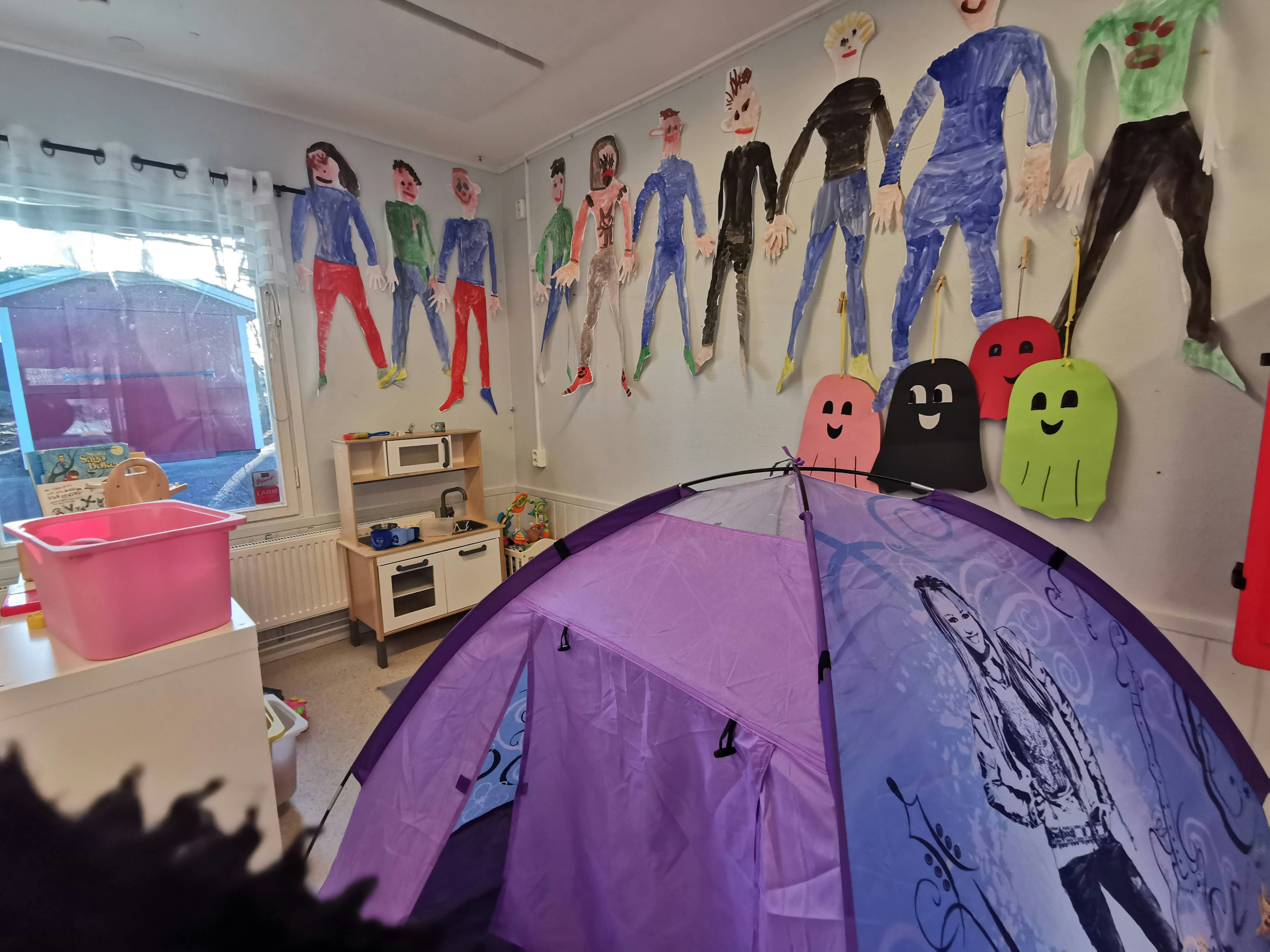 Playroom with purple tent and colorful character drawings on walls