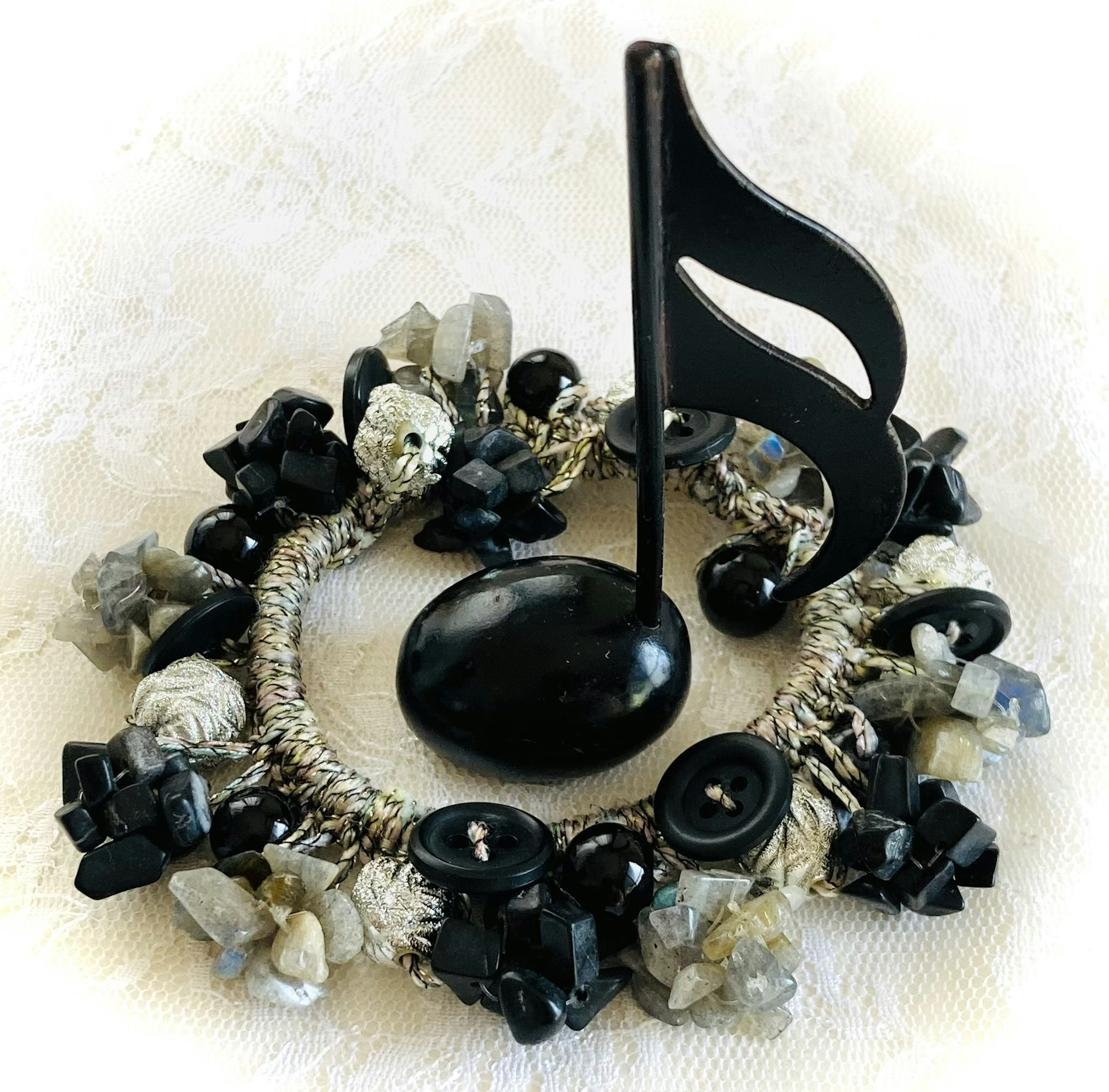 Black musical note surrounded by a beaded wreath of stones